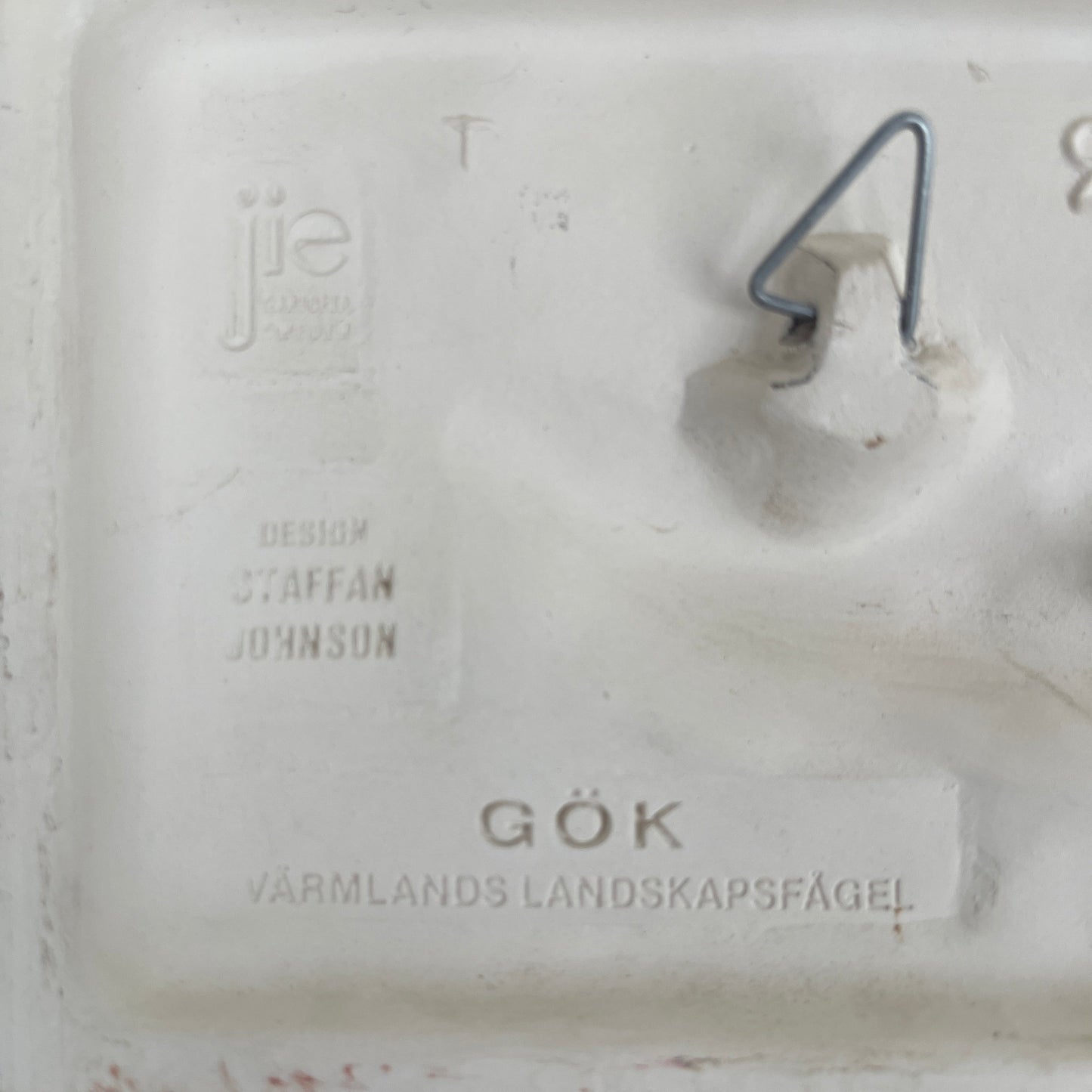 Close-up of a white ceramic item with engraved text on a textured surface