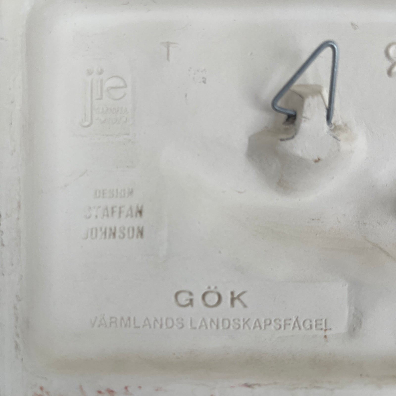 Close-up of a white ceramic item with engraved text on a textured surface