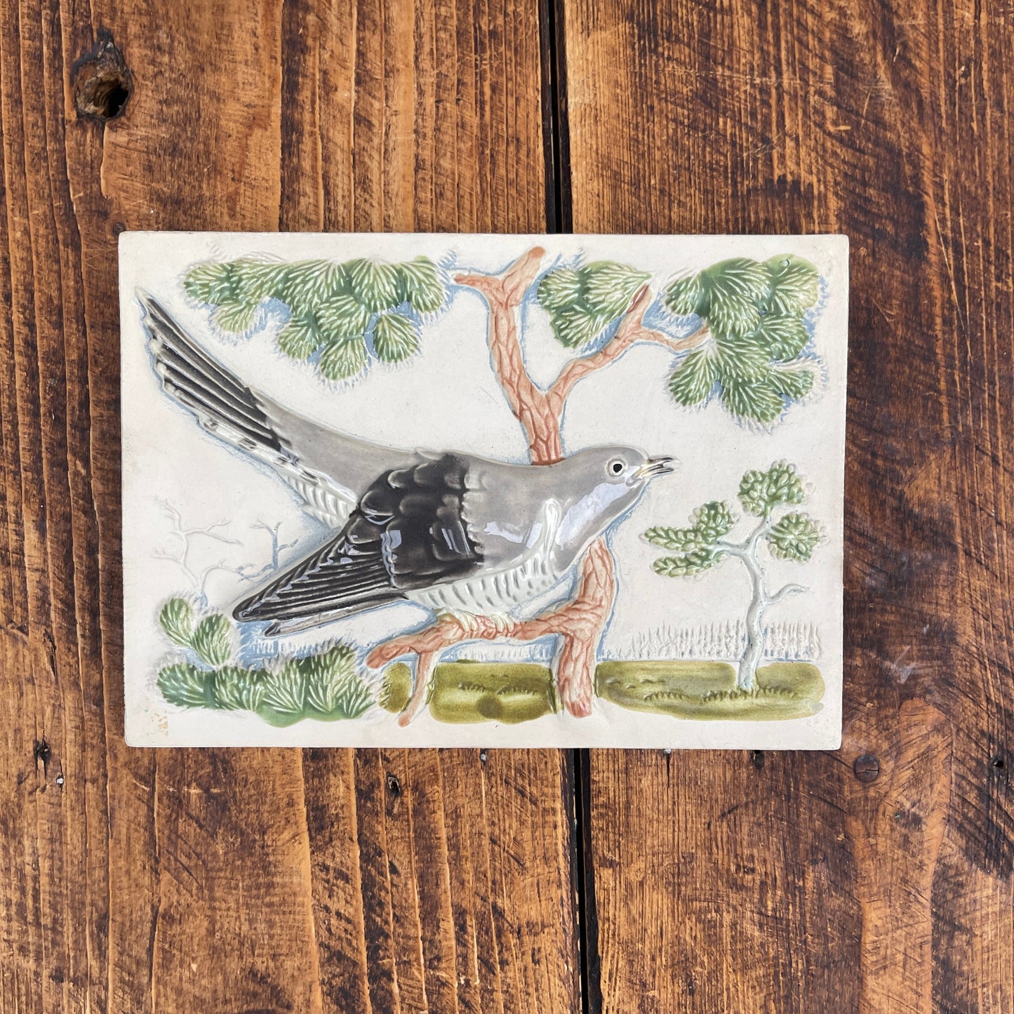 Decorative tile with a bird design on a wooden surface