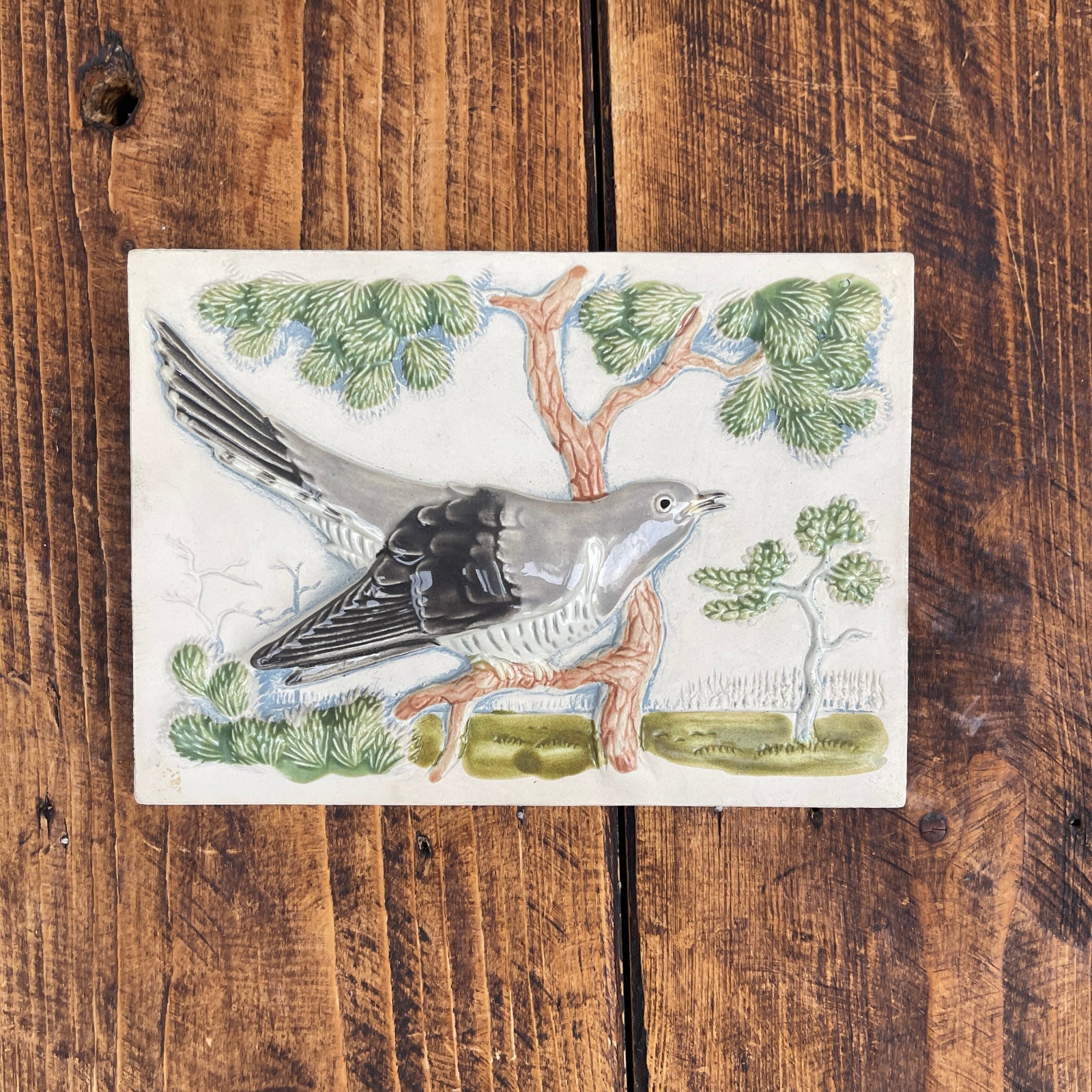 Decorative tile with a bird design on a wooden surface
