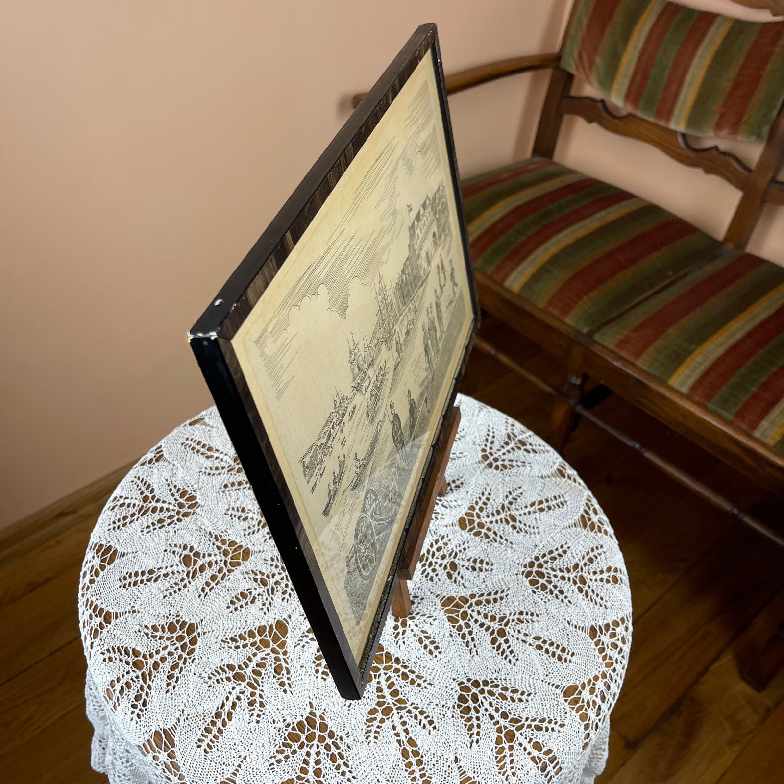 Framed map on a small round table with a striped chair in the background