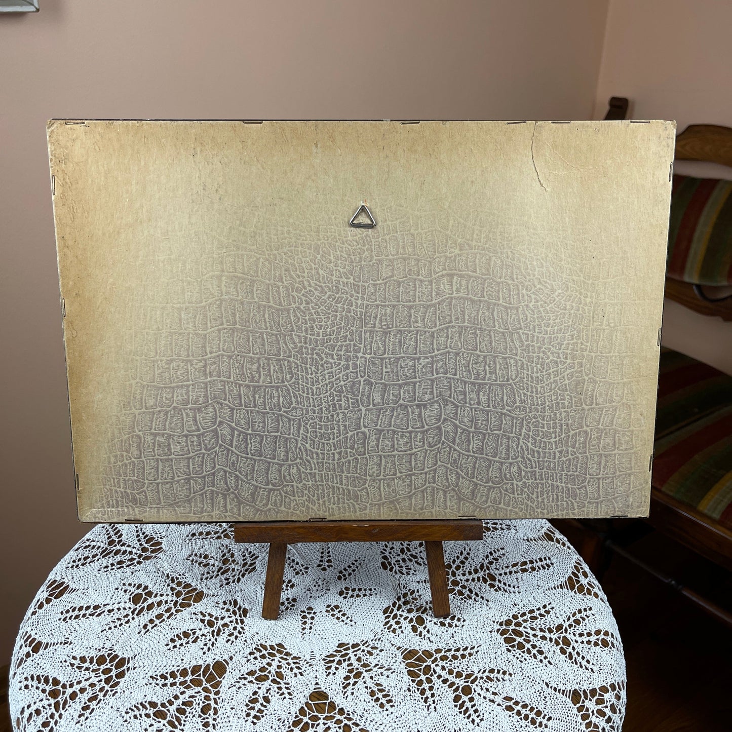 Textured beige board on a wooden easel with a triangle emblem, placed on a lace tablecloth.