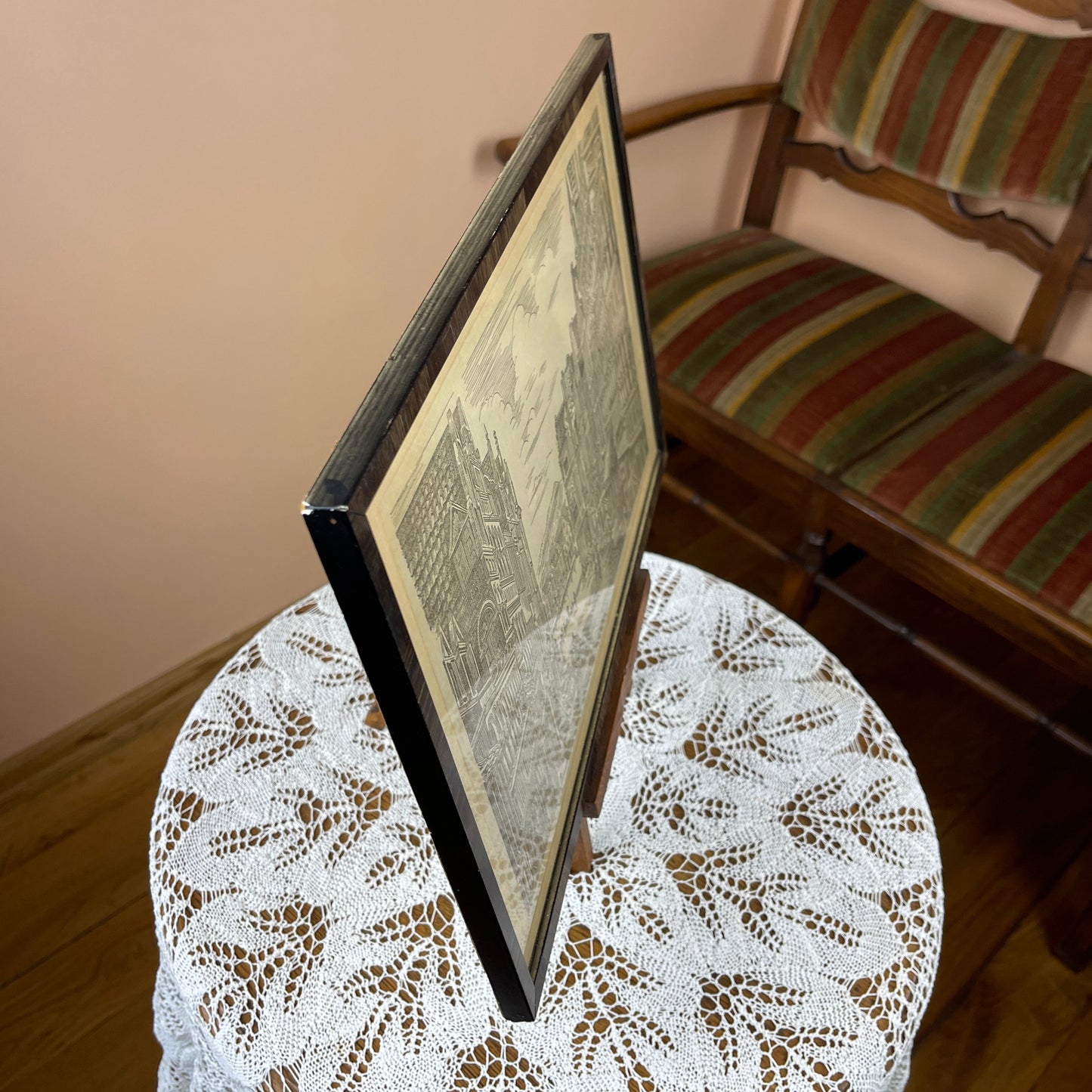 Framed document on a lace tablecloth with a striped chair in the background