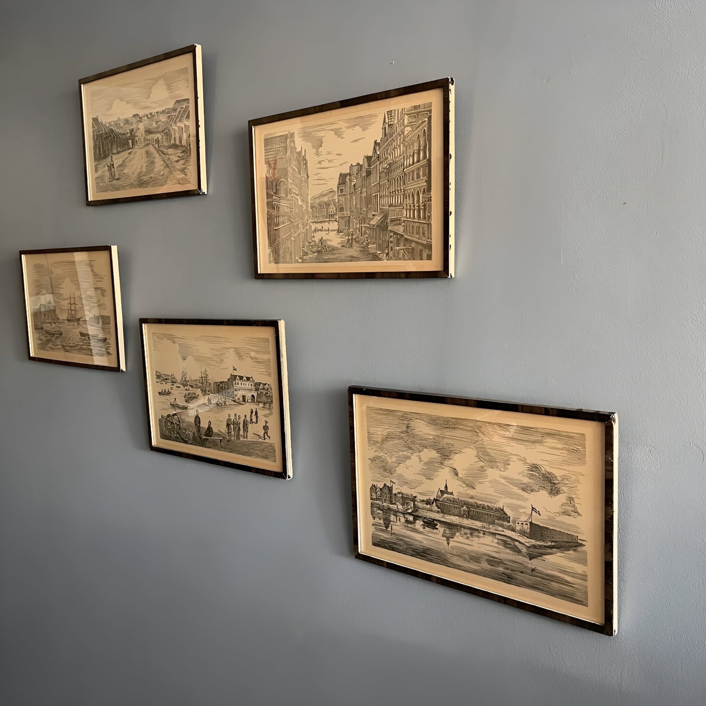 Five framed vintage-style cityscape prints on a gray wall.