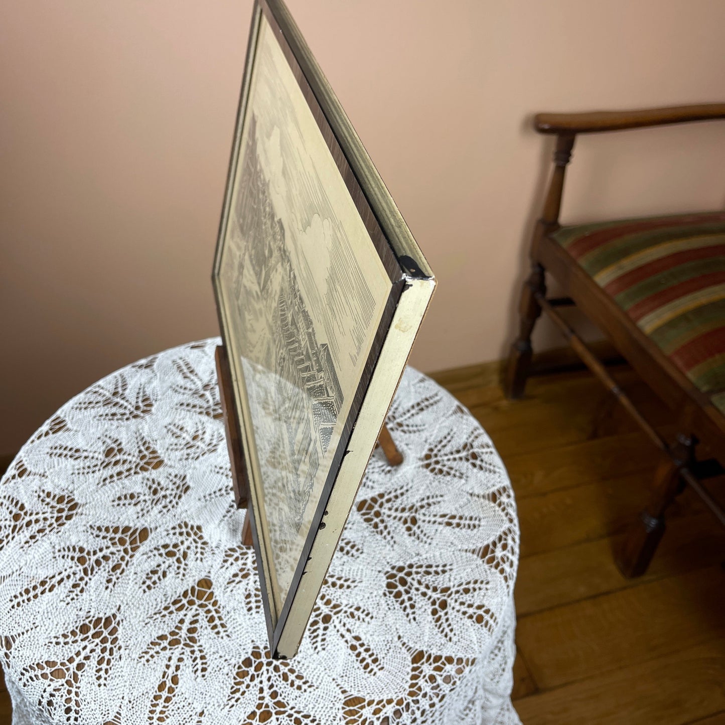 Framed picture on a lace tablecloth with a chair in the background