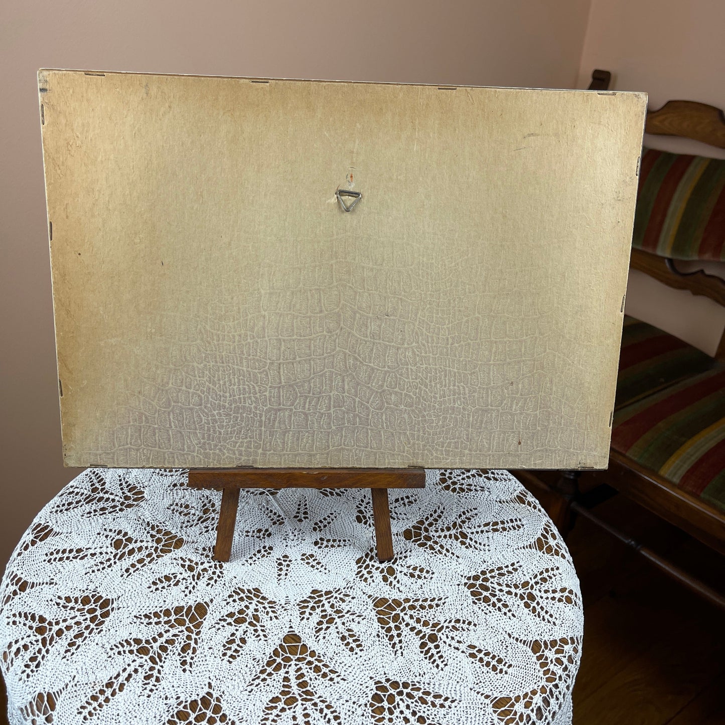 Wooden easel with a textured white board on a table with a lace tablecloth.