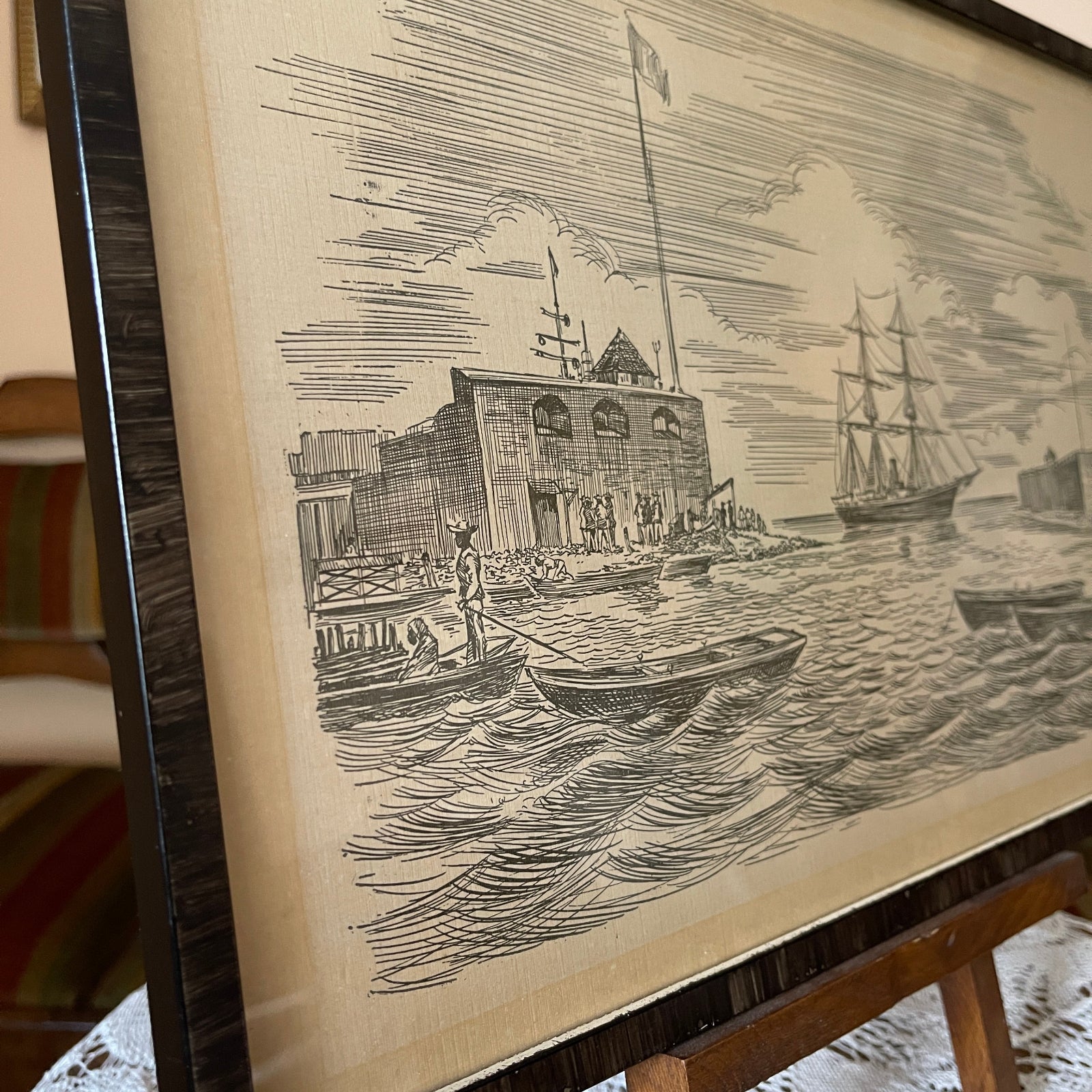 Framed black and white print of a coastal scene with buildings and boats.