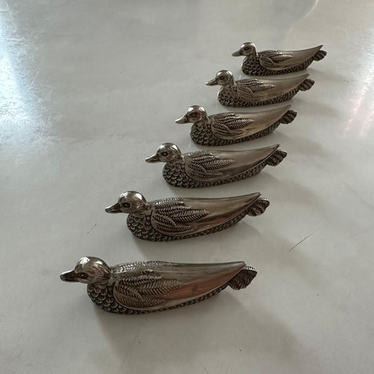 Set of six metallic duck-shaped objects on a reflective surface