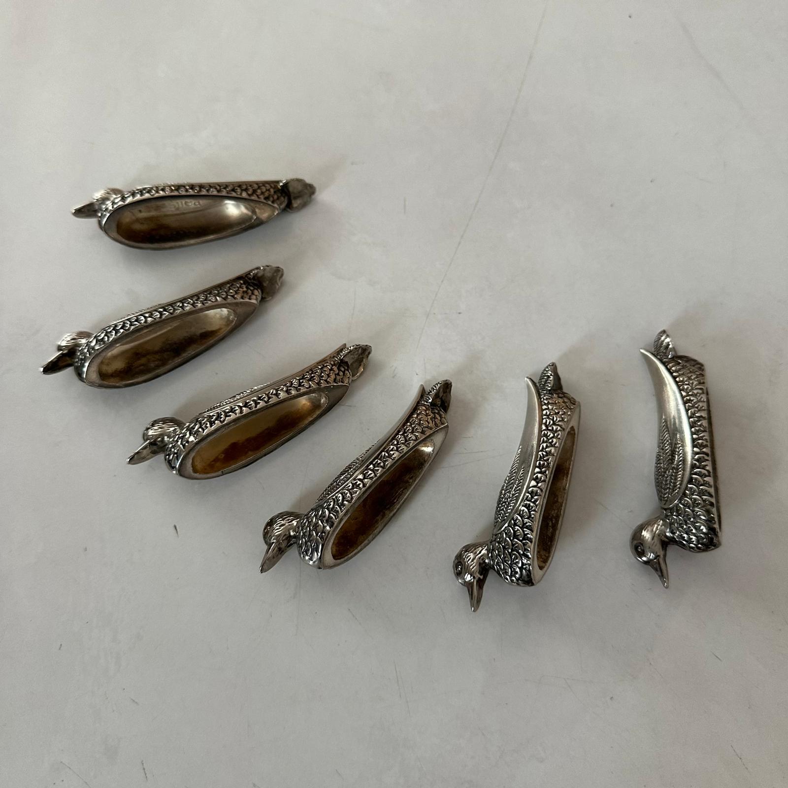 Set of silver bird-shaped decorative items on a white surface