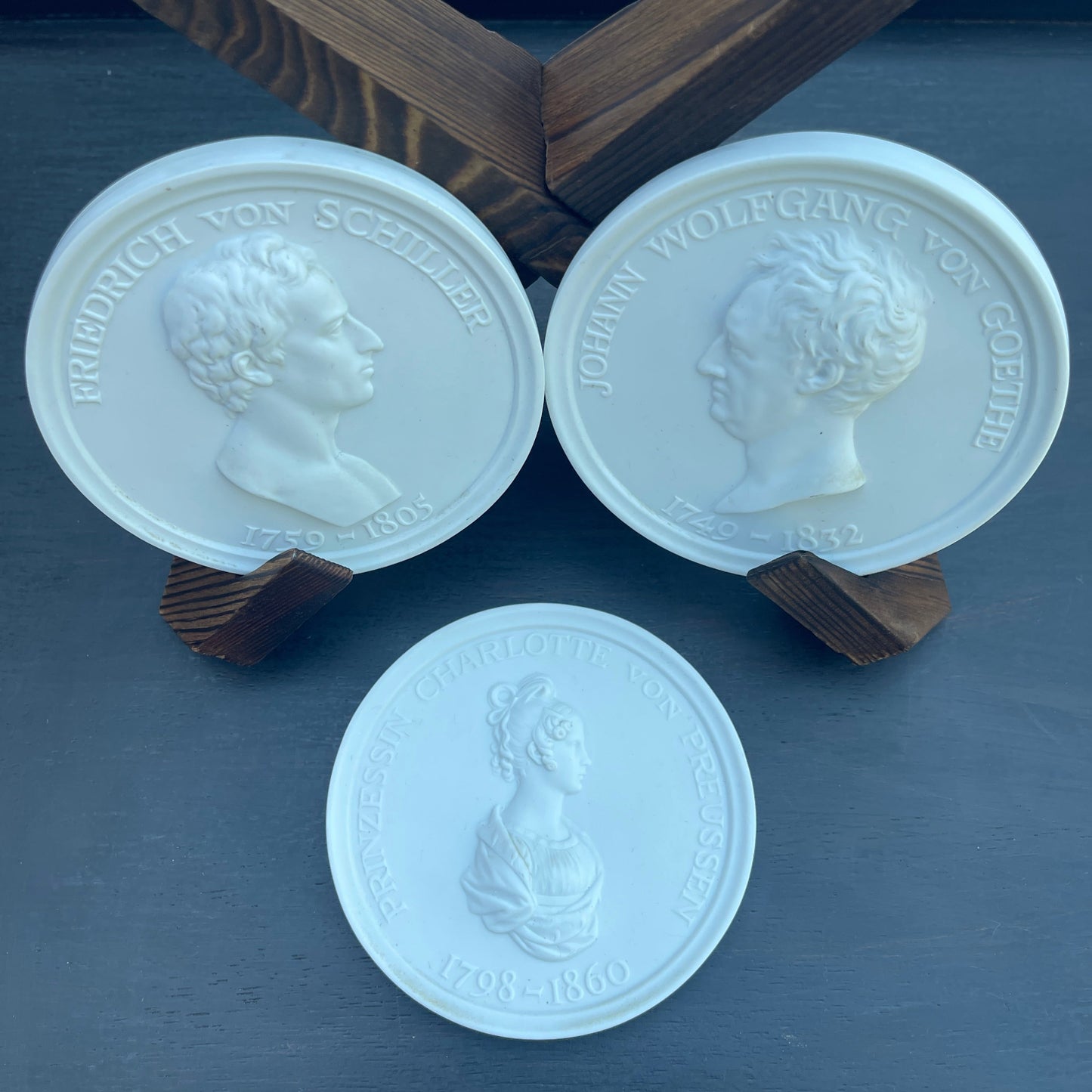 Three white stone medallions with engraved faces on a dark surface.