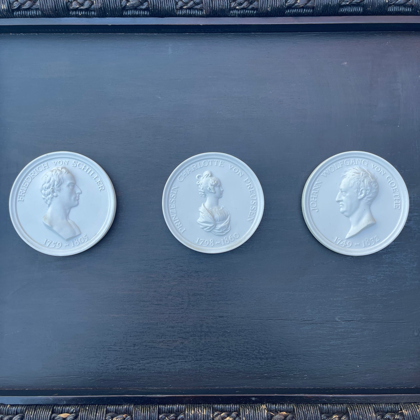 Three silver coins with portraits on a dark blue background