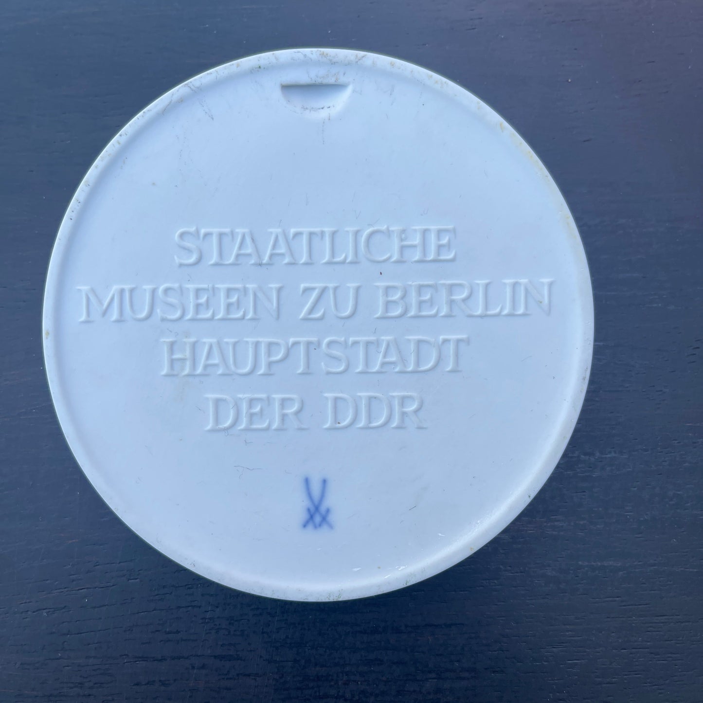 Round white object with engraved text on a dark blue background