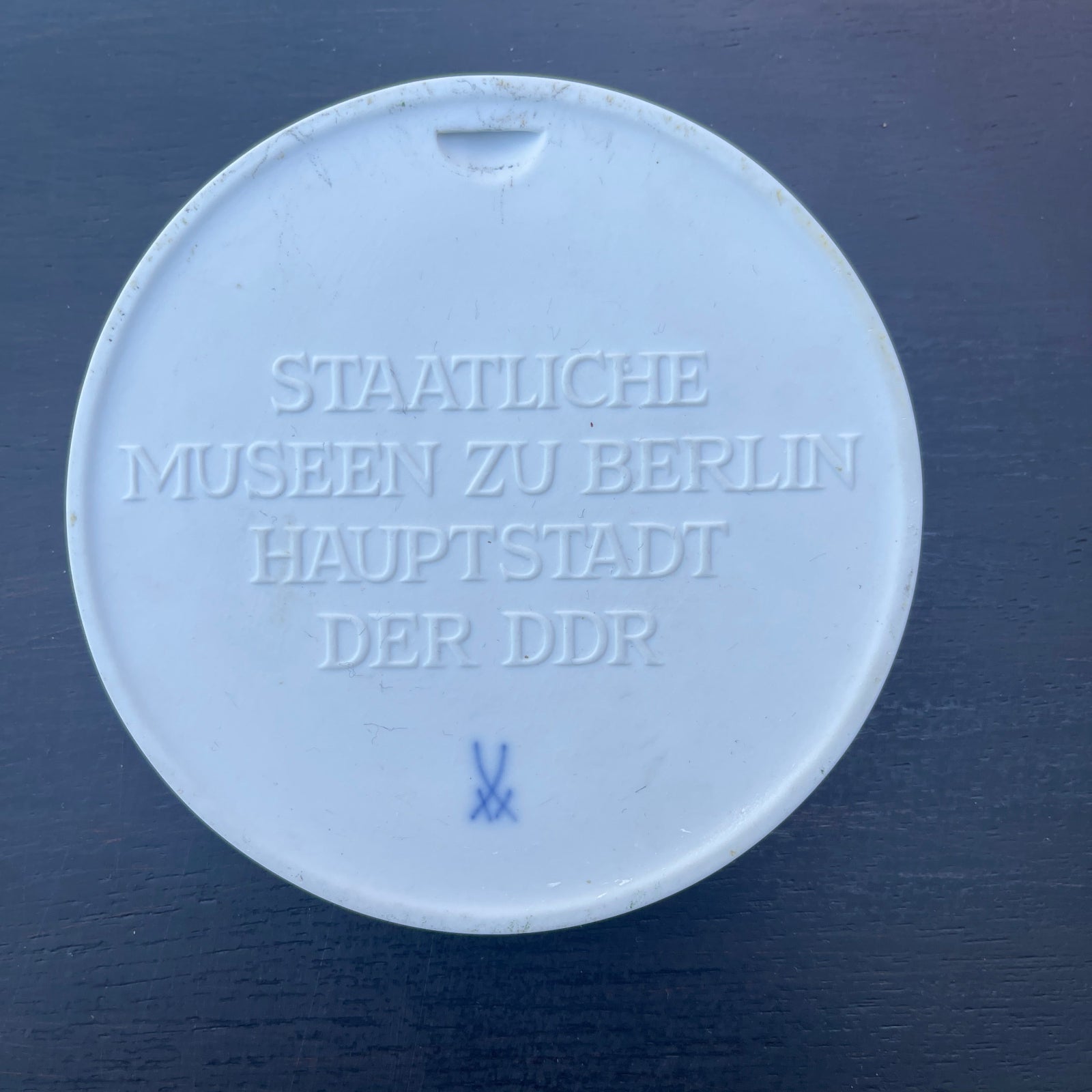 Round white object with engraved text on a dark blue background