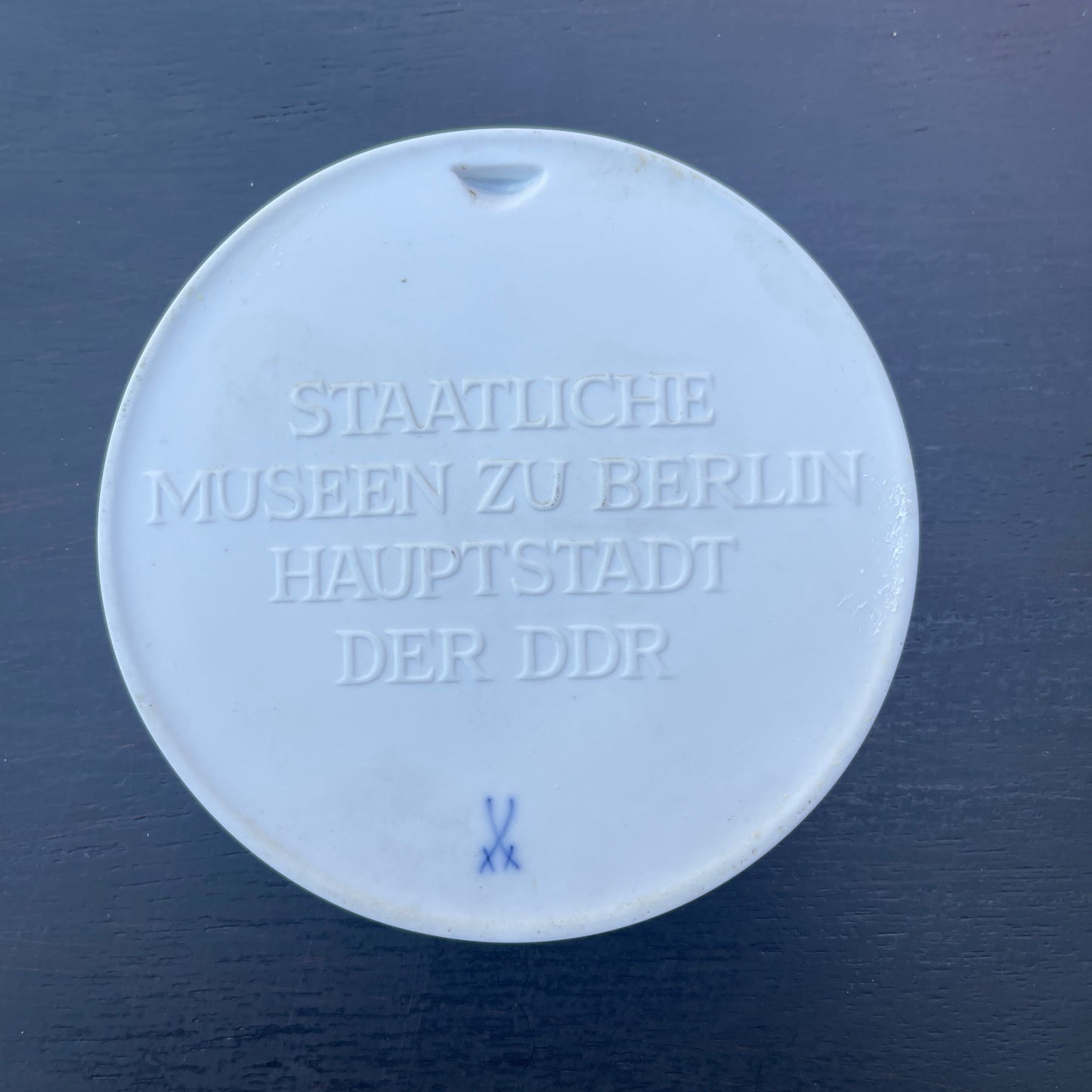 Round white object with embossed text on a dark blue background