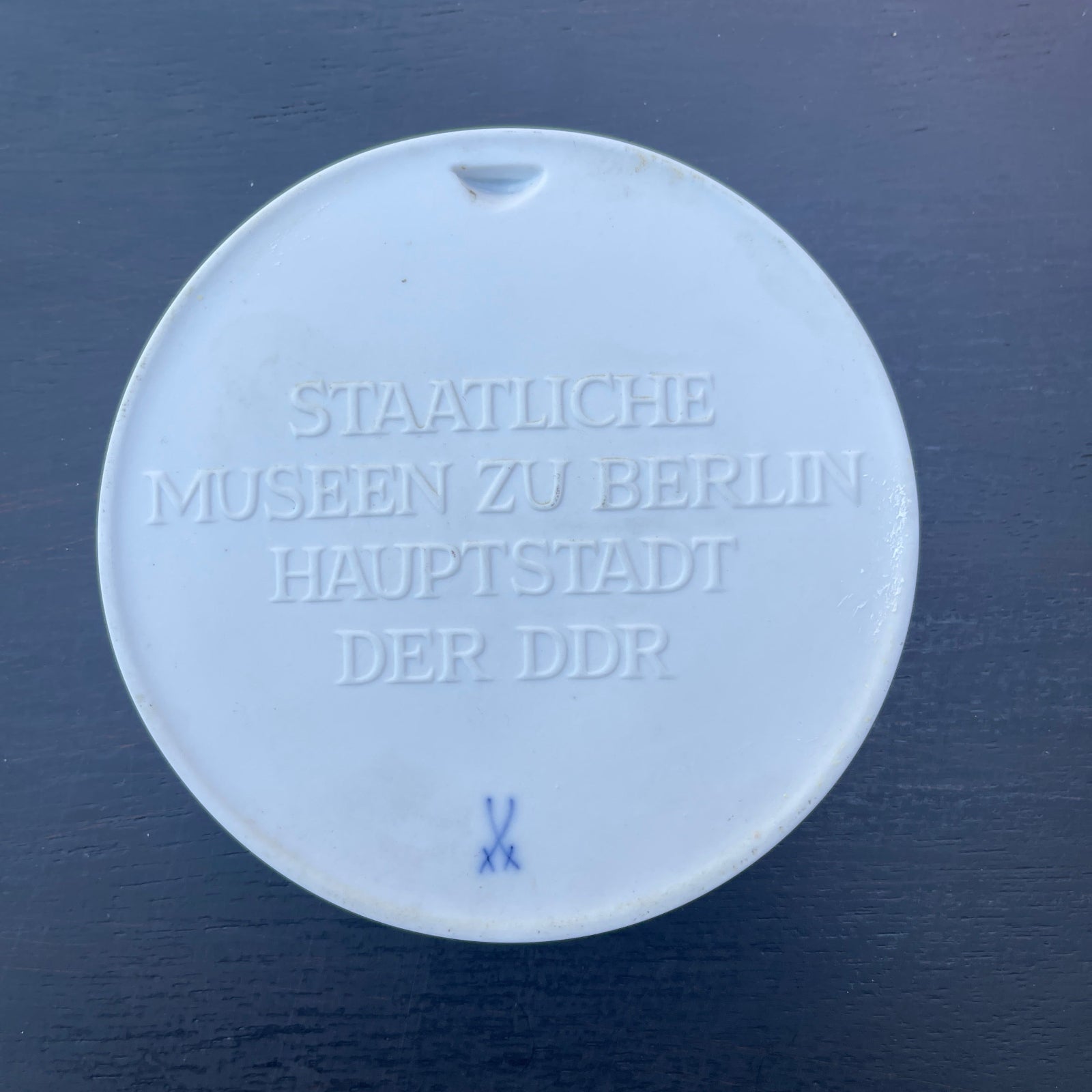 Round white object with embossed text on a dark blue background