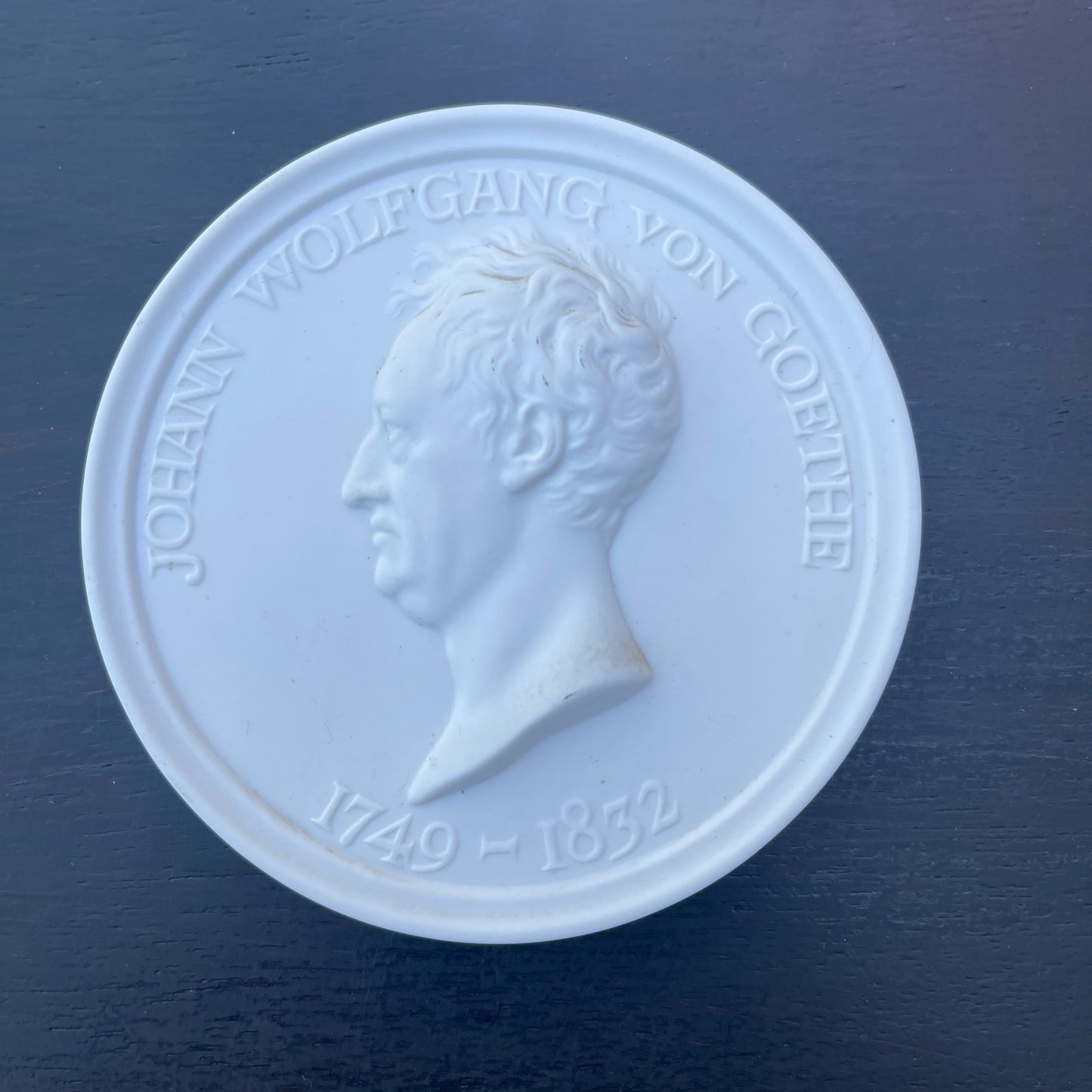 Medallion with a profile of a person and text on a dark blue background