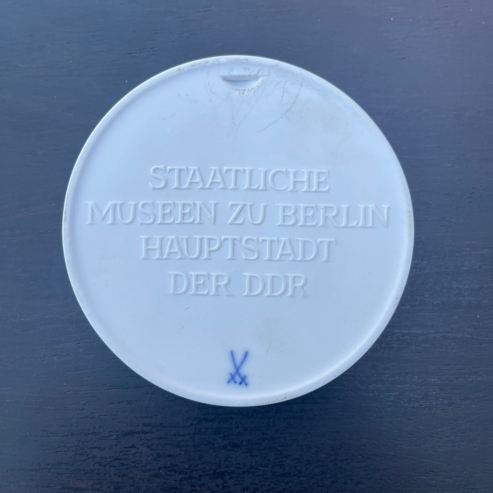 Round white object with embossed text on a dark blue background