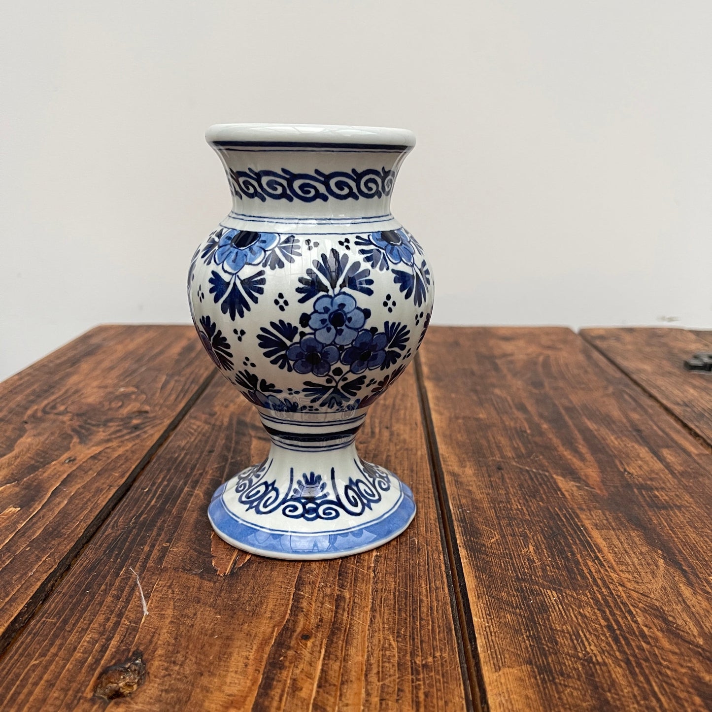 Blue and white floral-patterned vase on a wooden surface with a white background