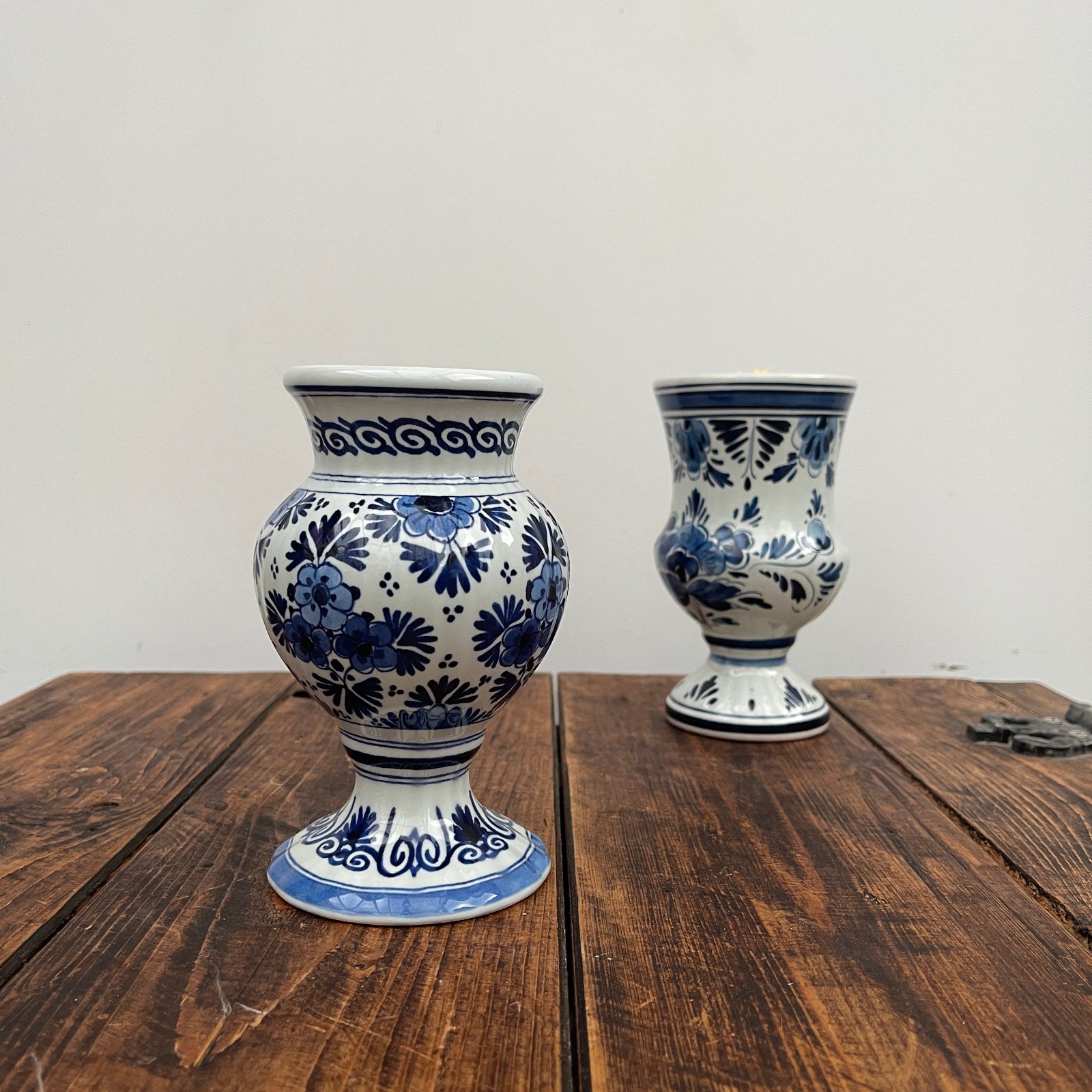 Two blue and white ceramic vases on a wooden surface with a plain background