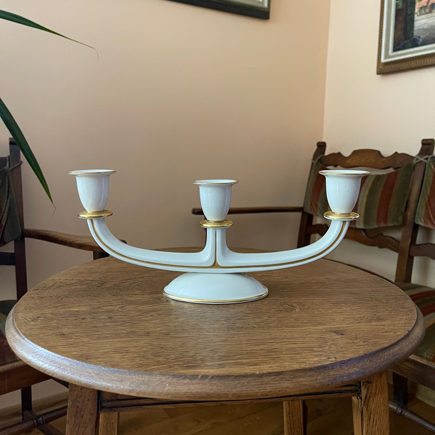 White candelabrum with gold accents on a wooden table in a room setting.