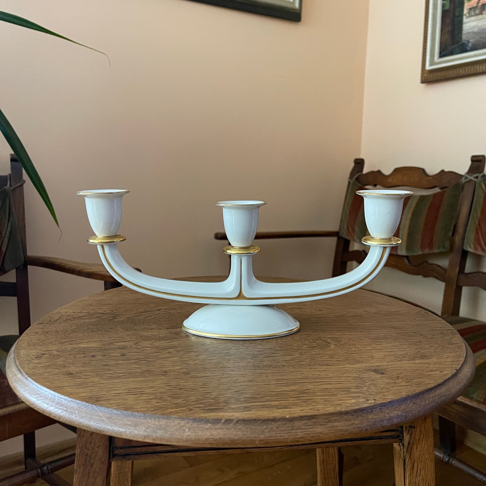 White candelabrum with gold accents on a wooden table in a room setting.