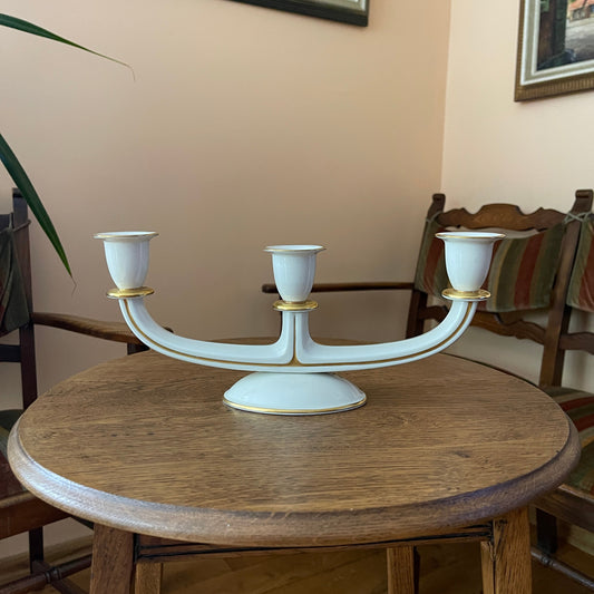 White candelabrum with gold accents on a wooden table in a room setting.