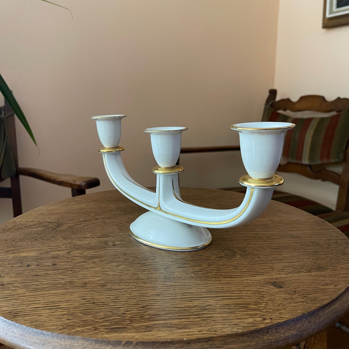 White and gold three-armed candle holder on a wooden table