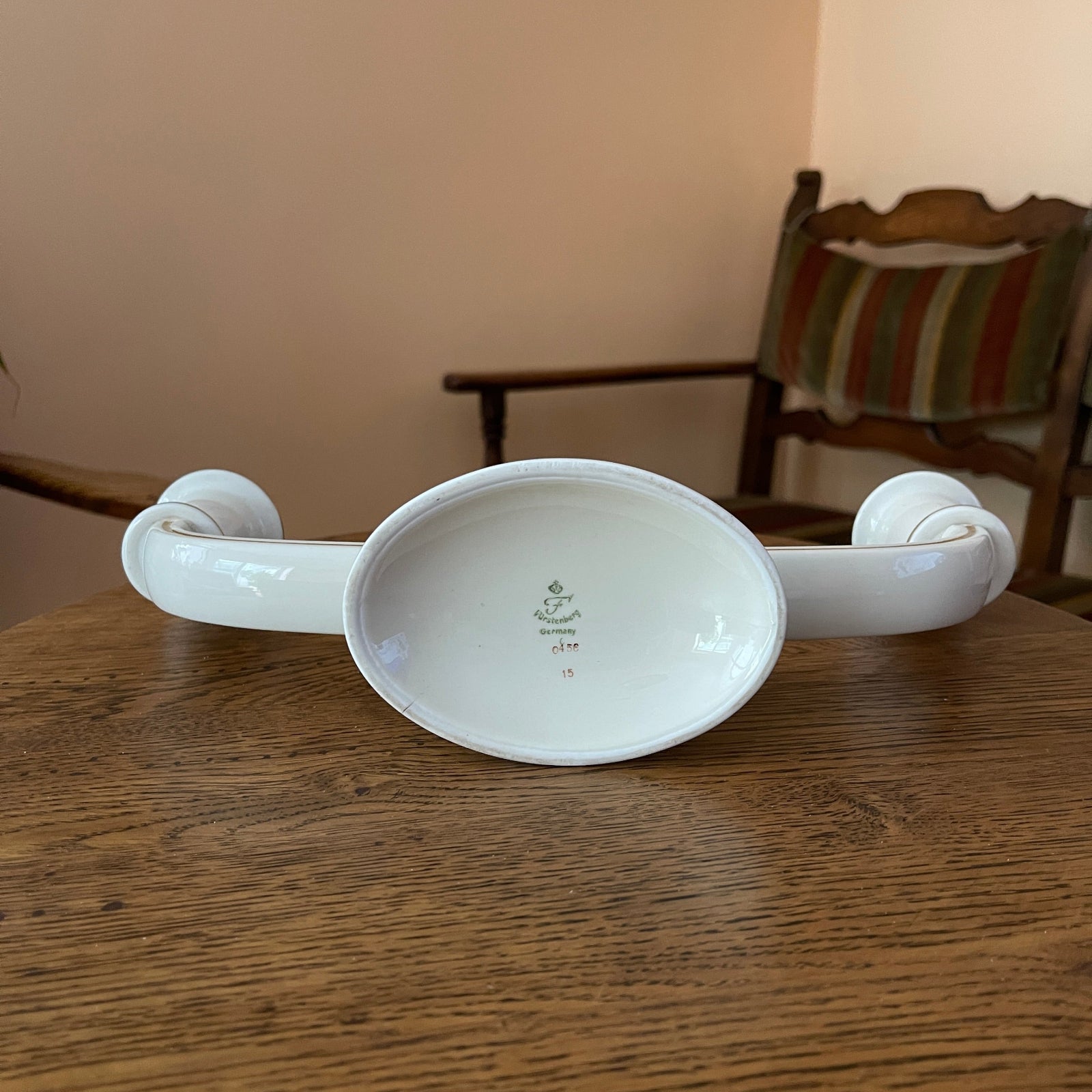 White ceramic bowl with handles on a wooden table