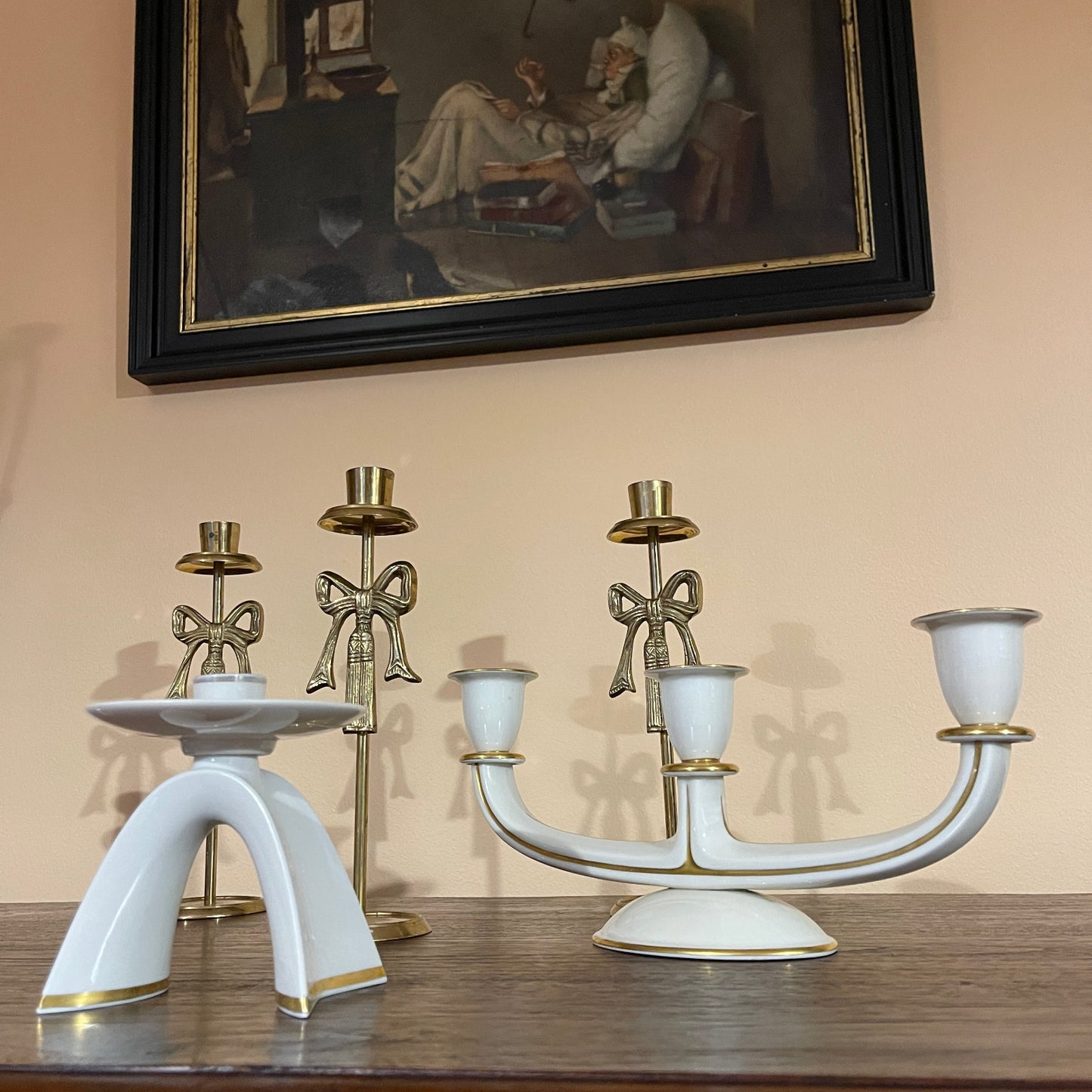 Decorative candle holders on a table with a painting in the background