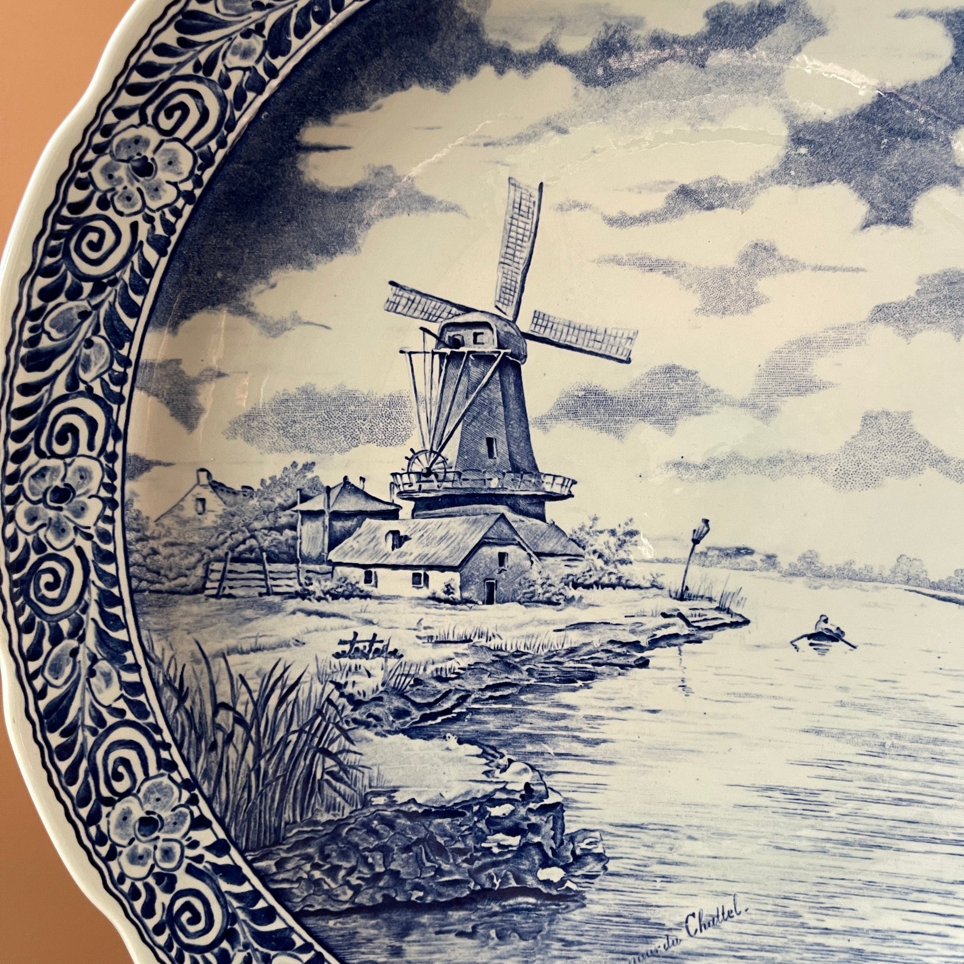 Decorative plate with a blue and white landscape design featuring a windmill.