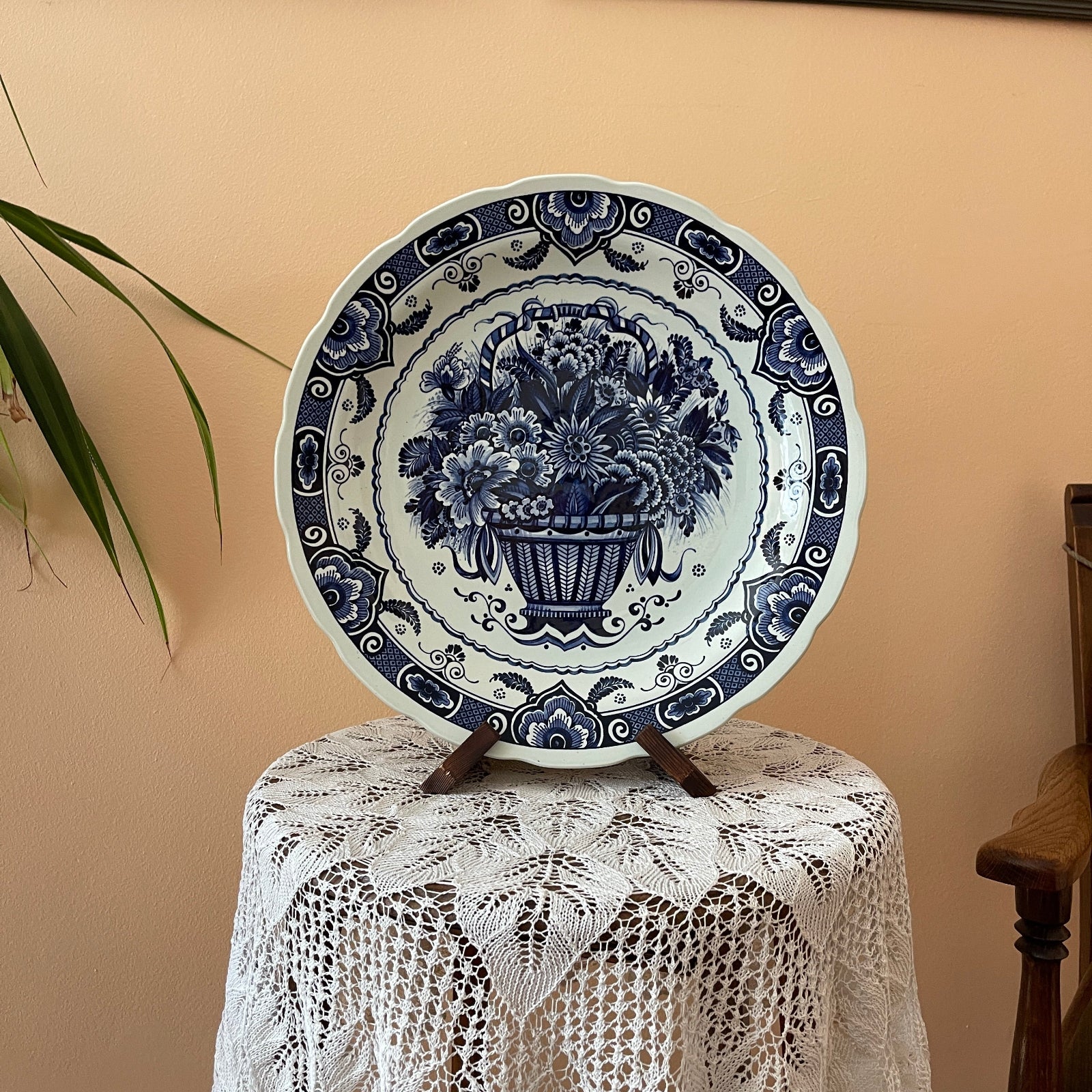 Decorative blue and white plate on a lace tablecloth with a plant in the background