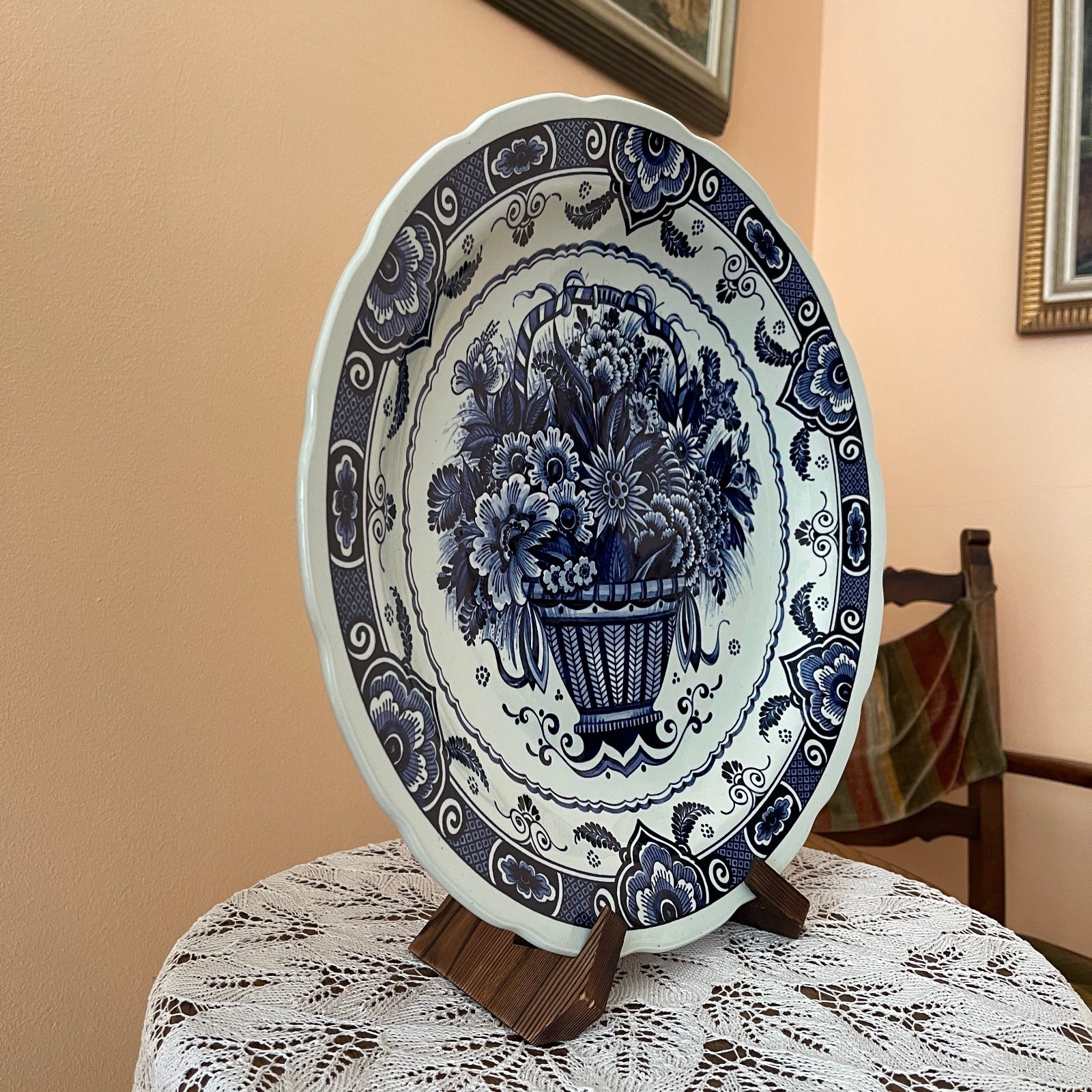 Decorative plate with floral design on a stand against a beige wall.