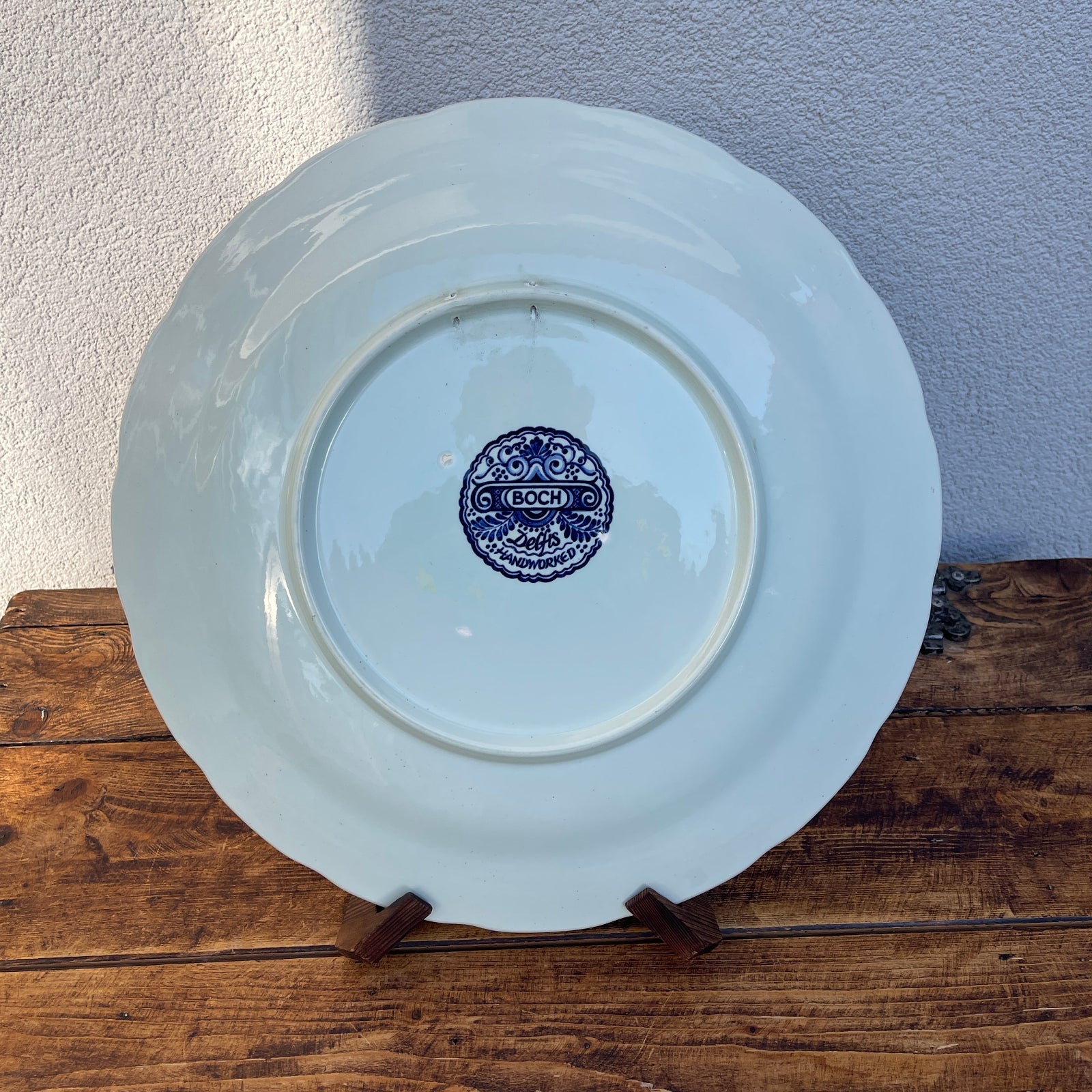 White plate with a blue logo on a wooden surface against a light purple wall
