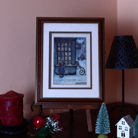 A framed 3D illustration of a boy in front of a store window, created by the Dutch artist Anton Pieck, displayed on a table with decorative items around it.