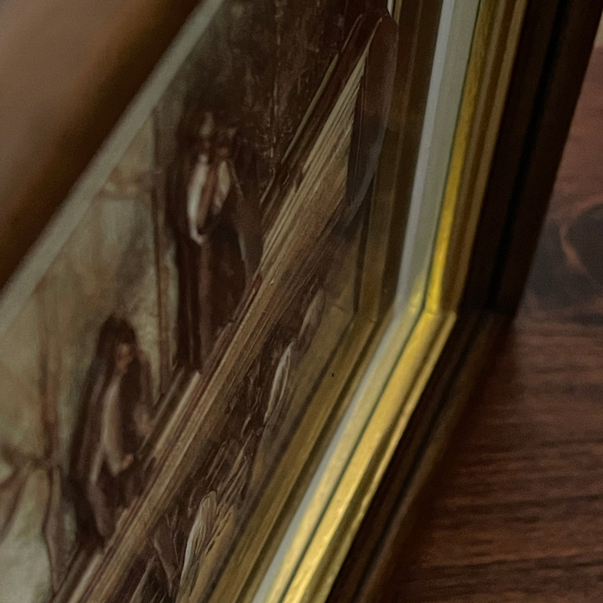 Close-up of a framed painting with a gold border on a wooden surface
