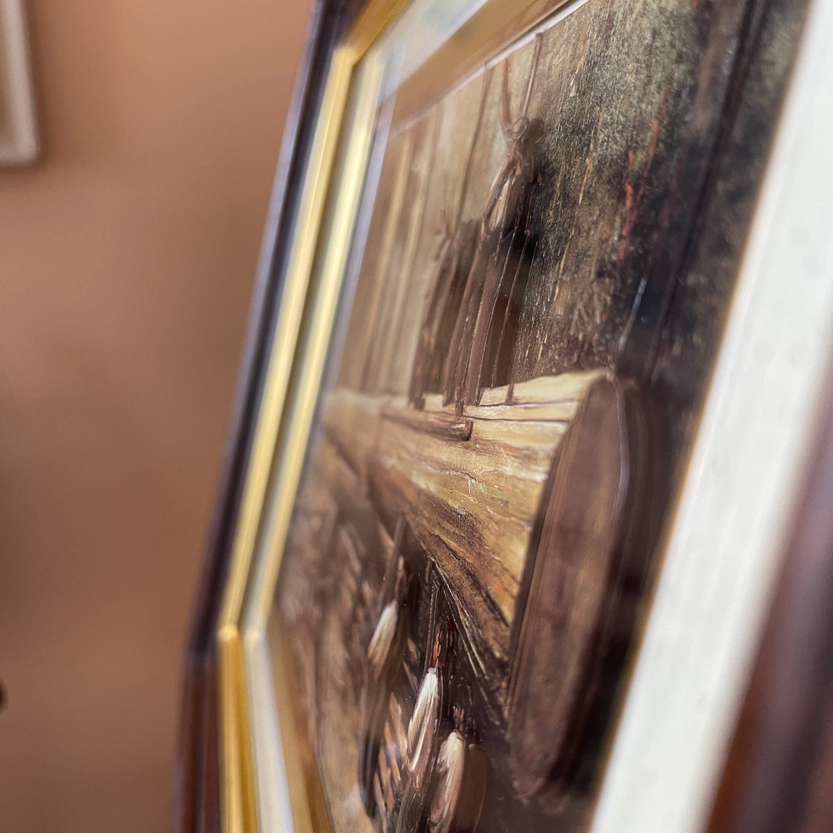 Close-up of a painting with a gold frame on a beige wall.