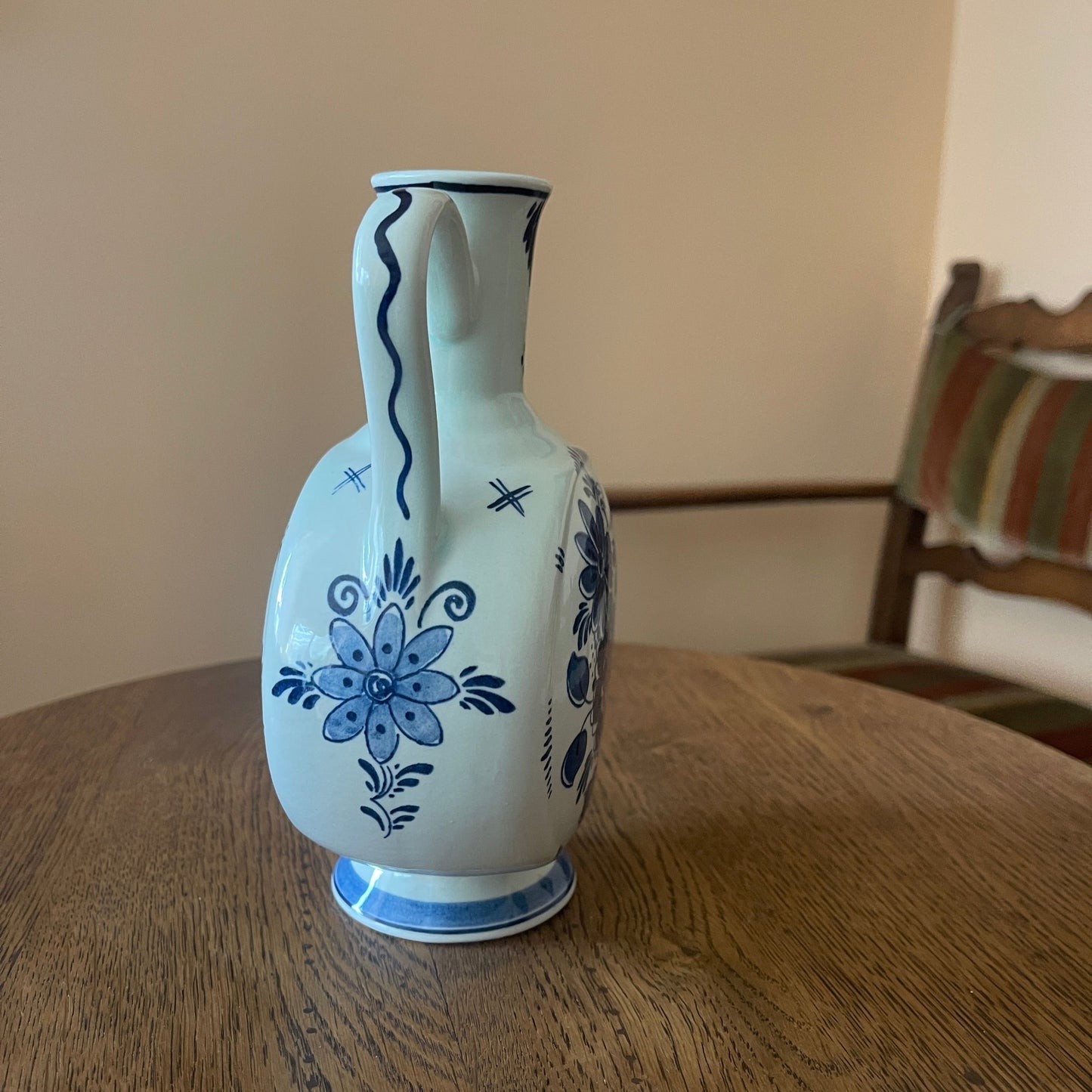 White ceramic pitcher with blue floral patterns on a wooden table.