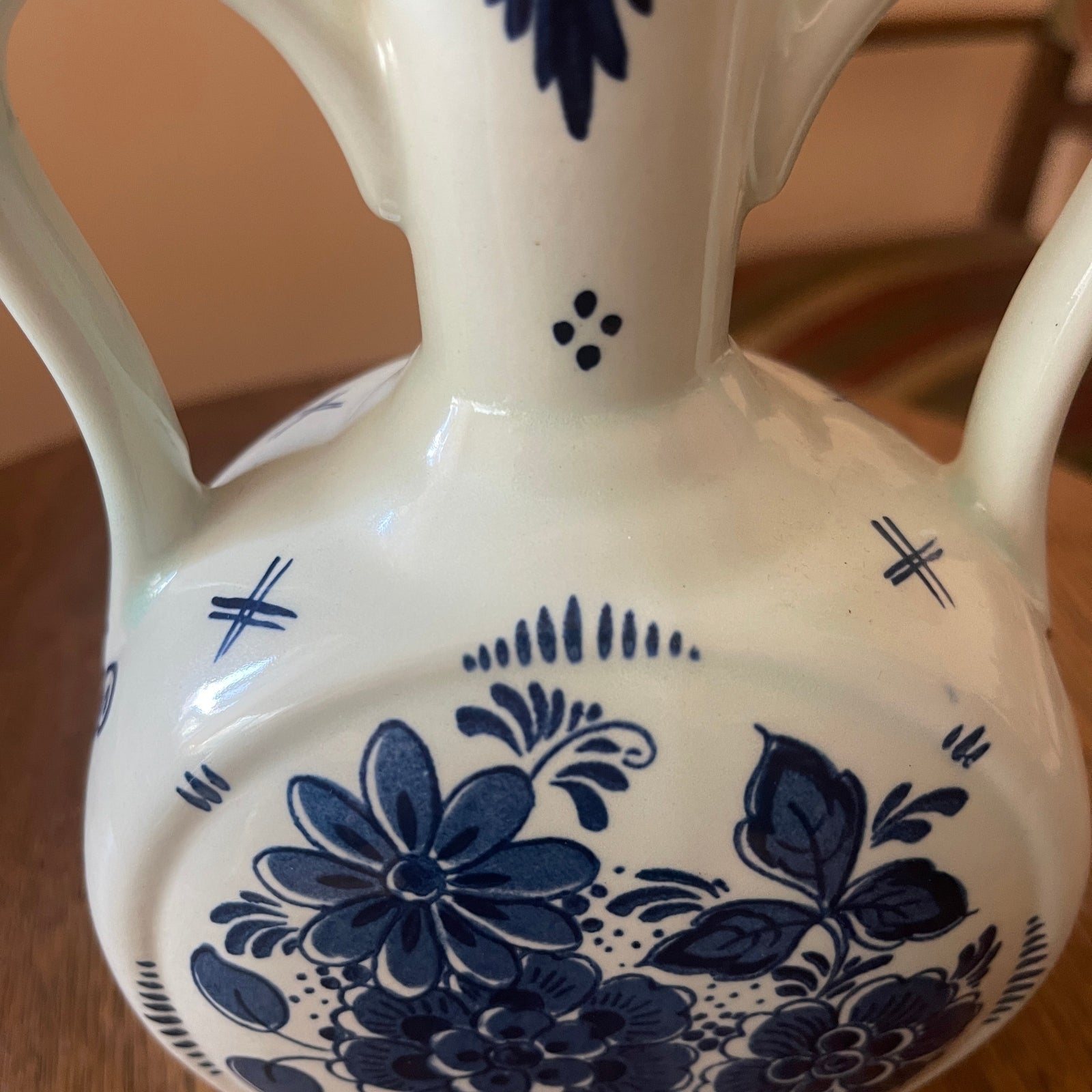 White ceramic vase with blue floral patterns on a wooden surface