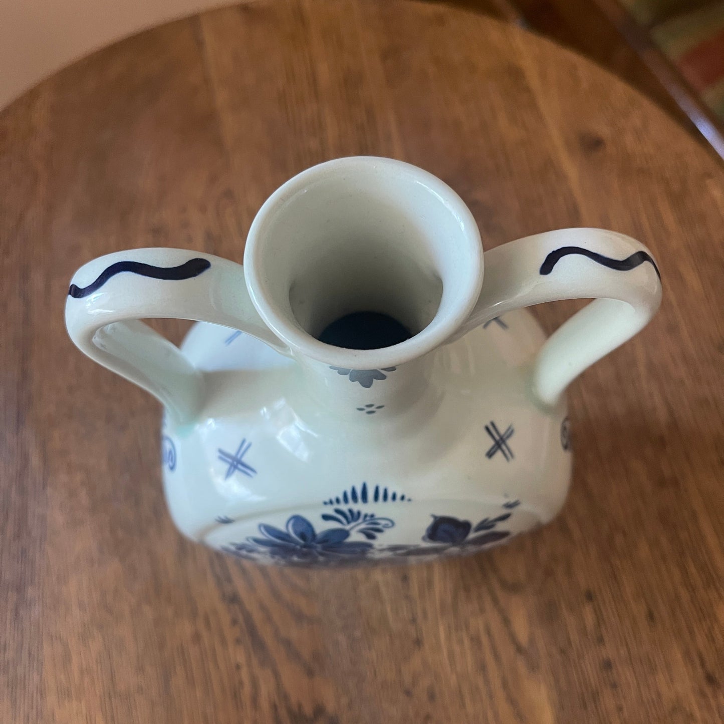 White ceramic vase with blue patterns on a wooden surface