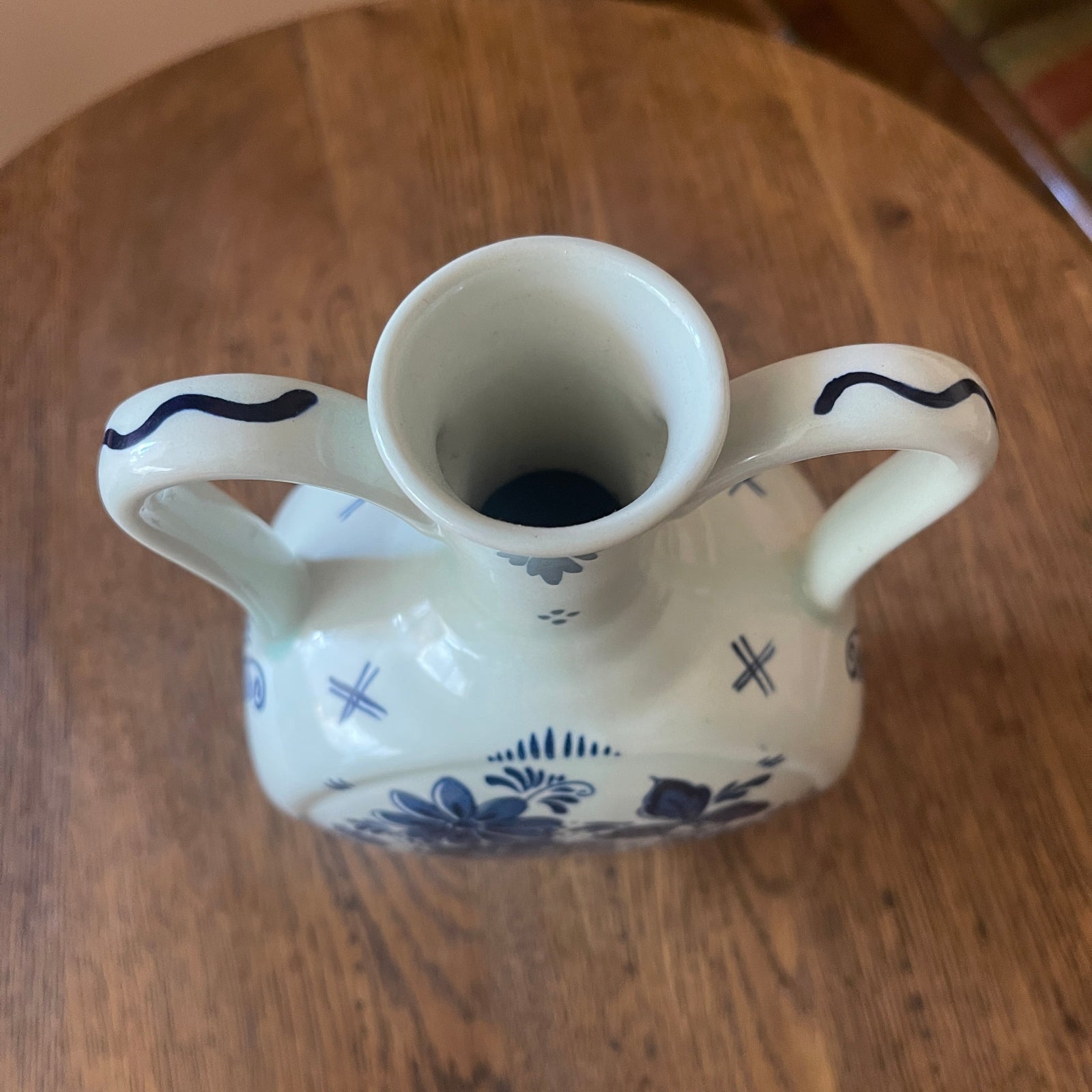 White ceramic vase with blue patterns on a wooden surface