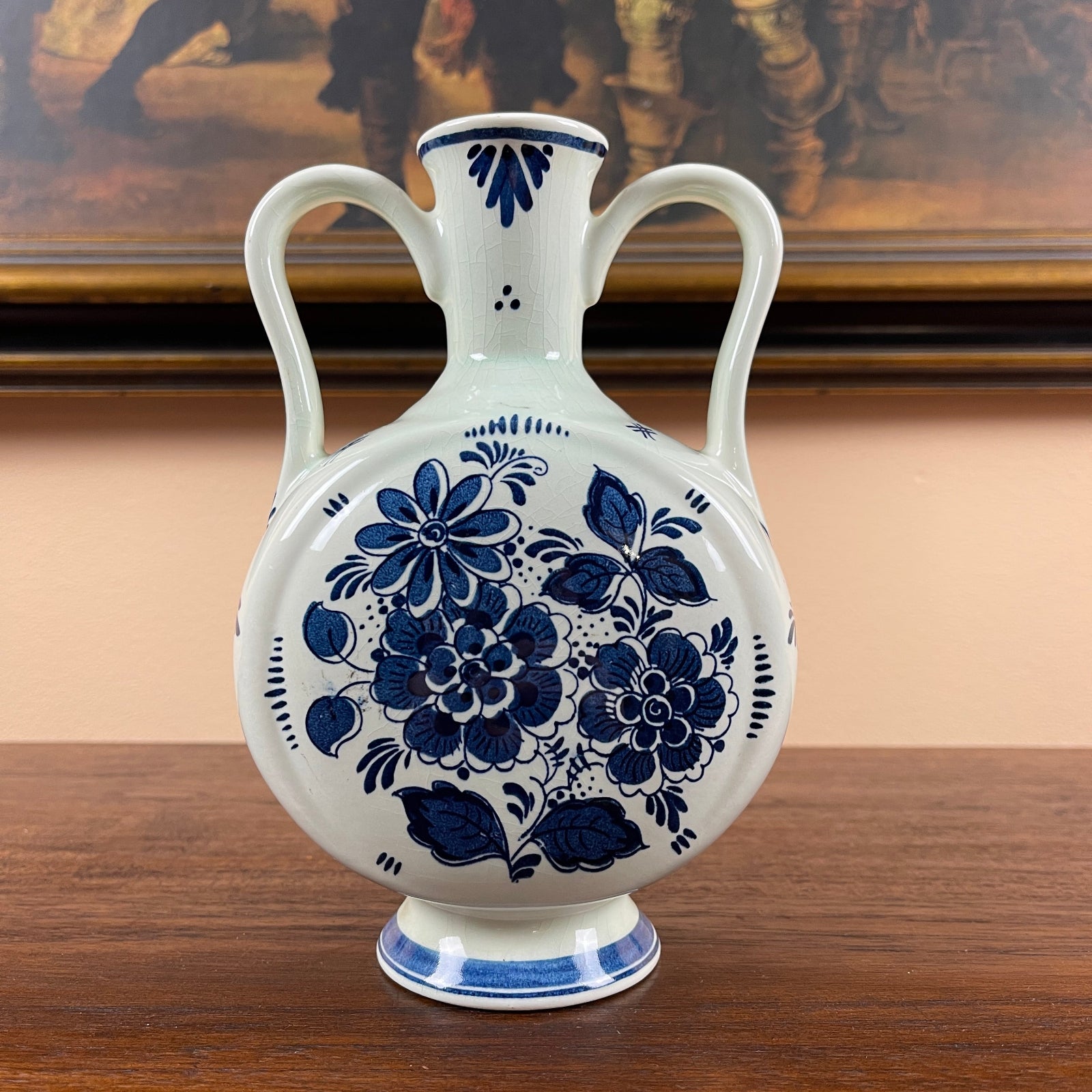White ceramic vase with blue floral patterns on a wooden surface.