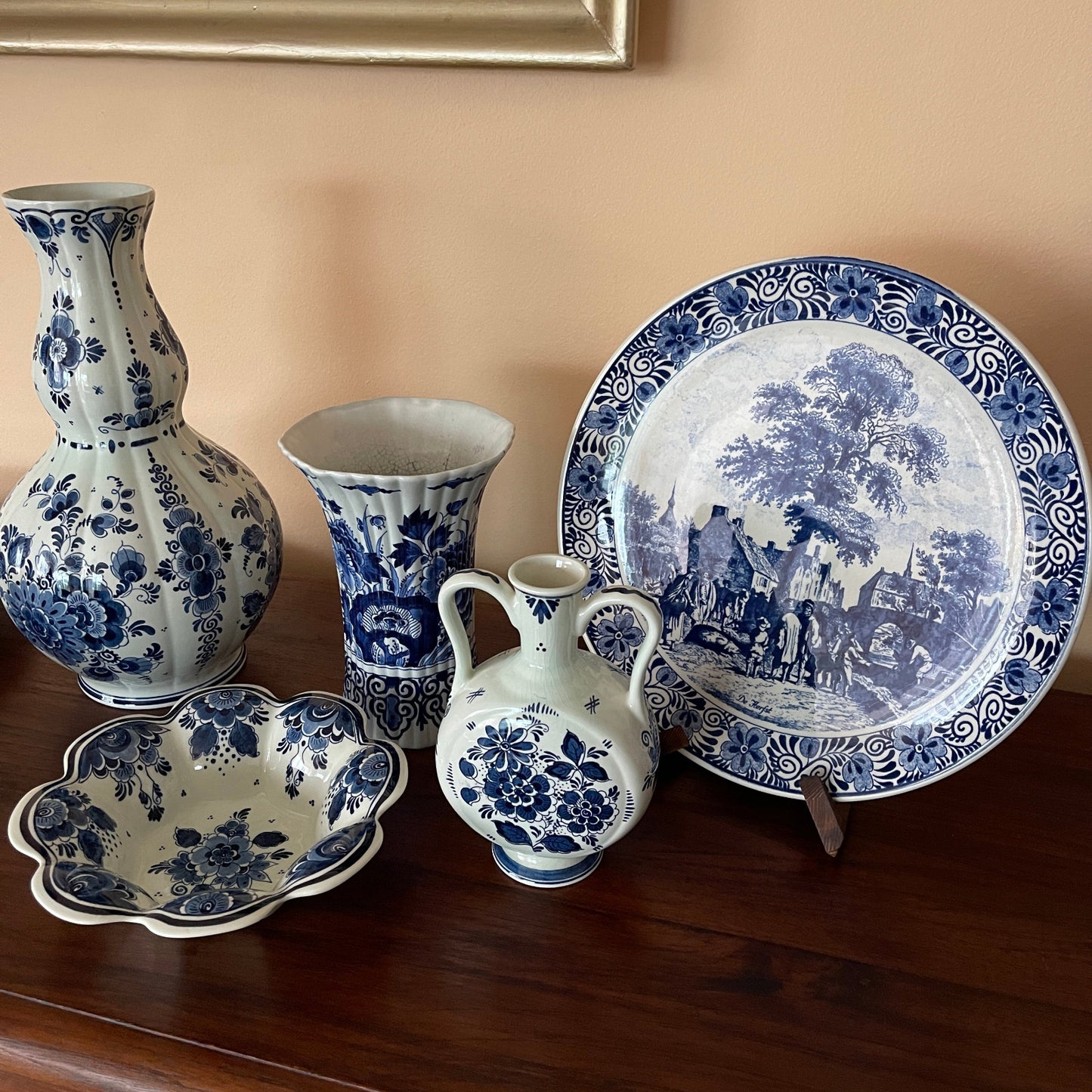 Set of blue and white ceramic items including a vase, plate, and bowls on a wooden surface.