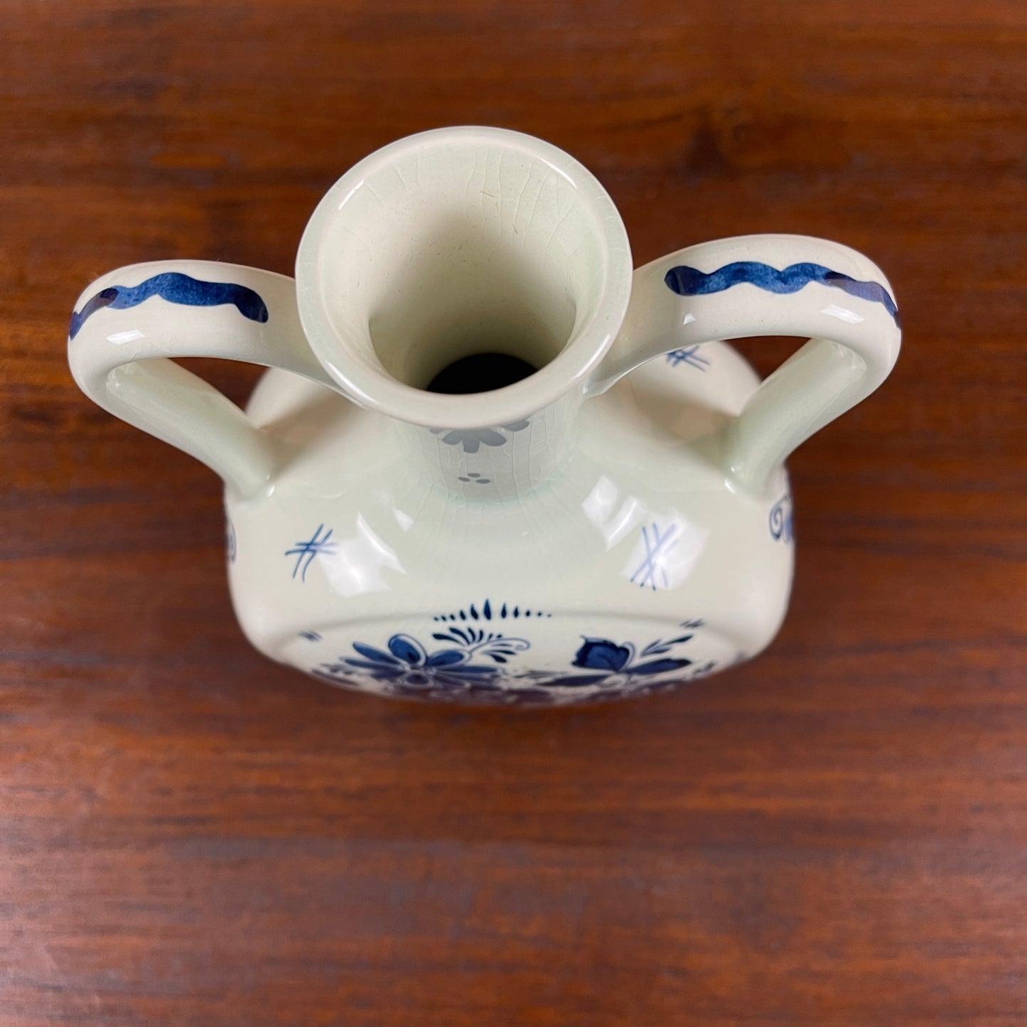 White ceramic vase with blue floral patterns on a wooden surface