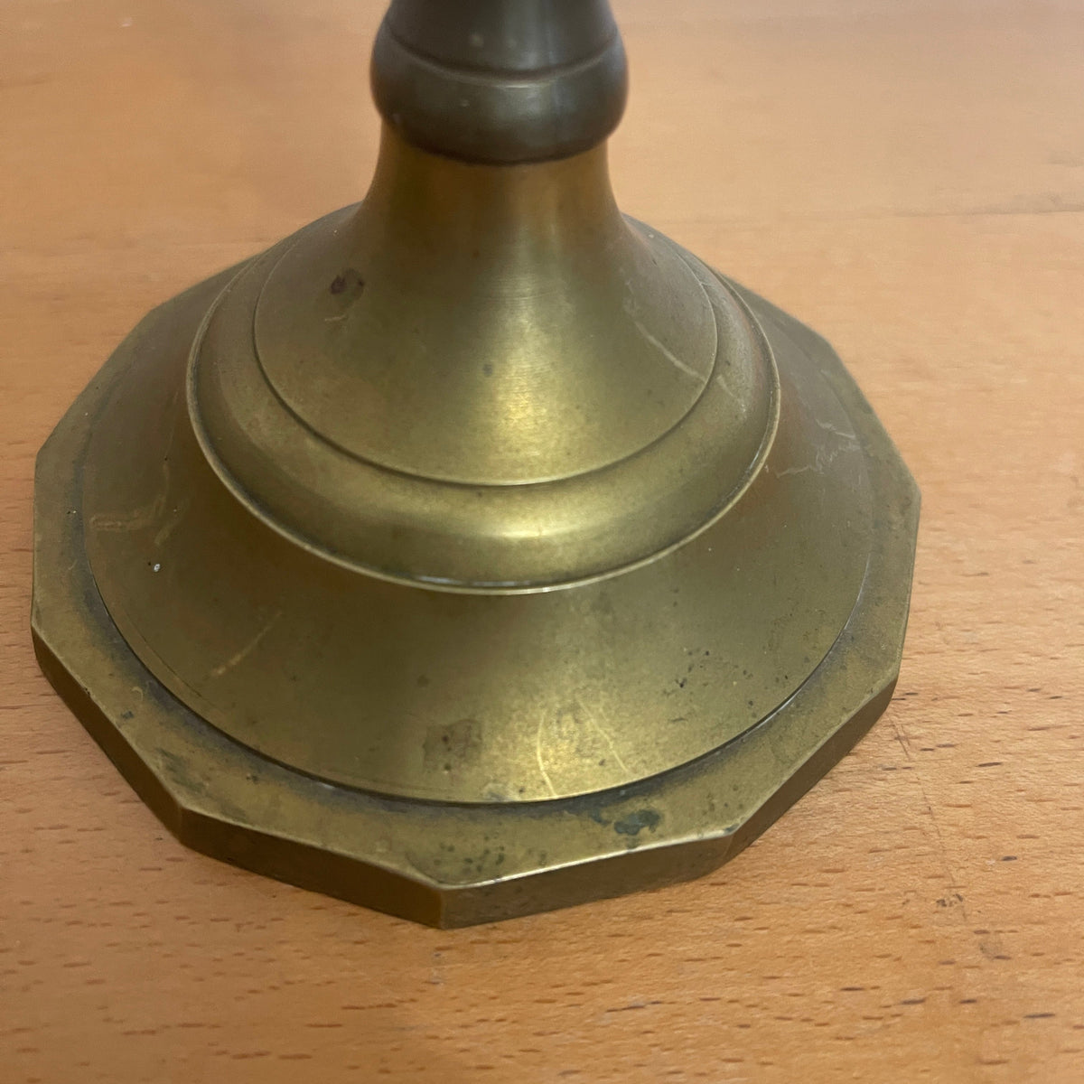 Brass candlestick base on a wooden surface