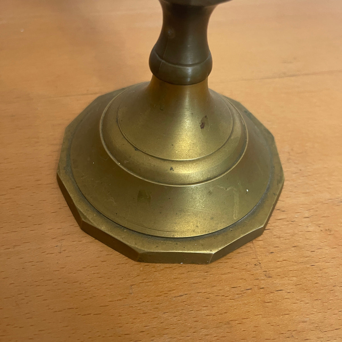 Brass candlestick base on a wooden surface