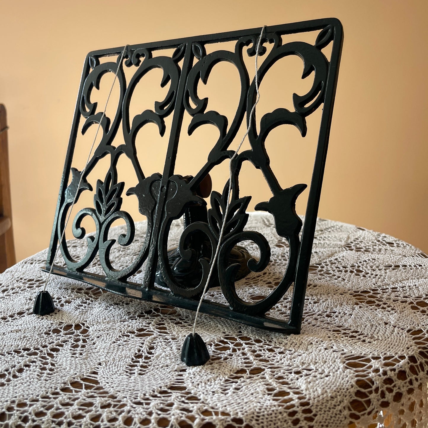 Decorative black metal book stand on a lace tablecloth with a beige background