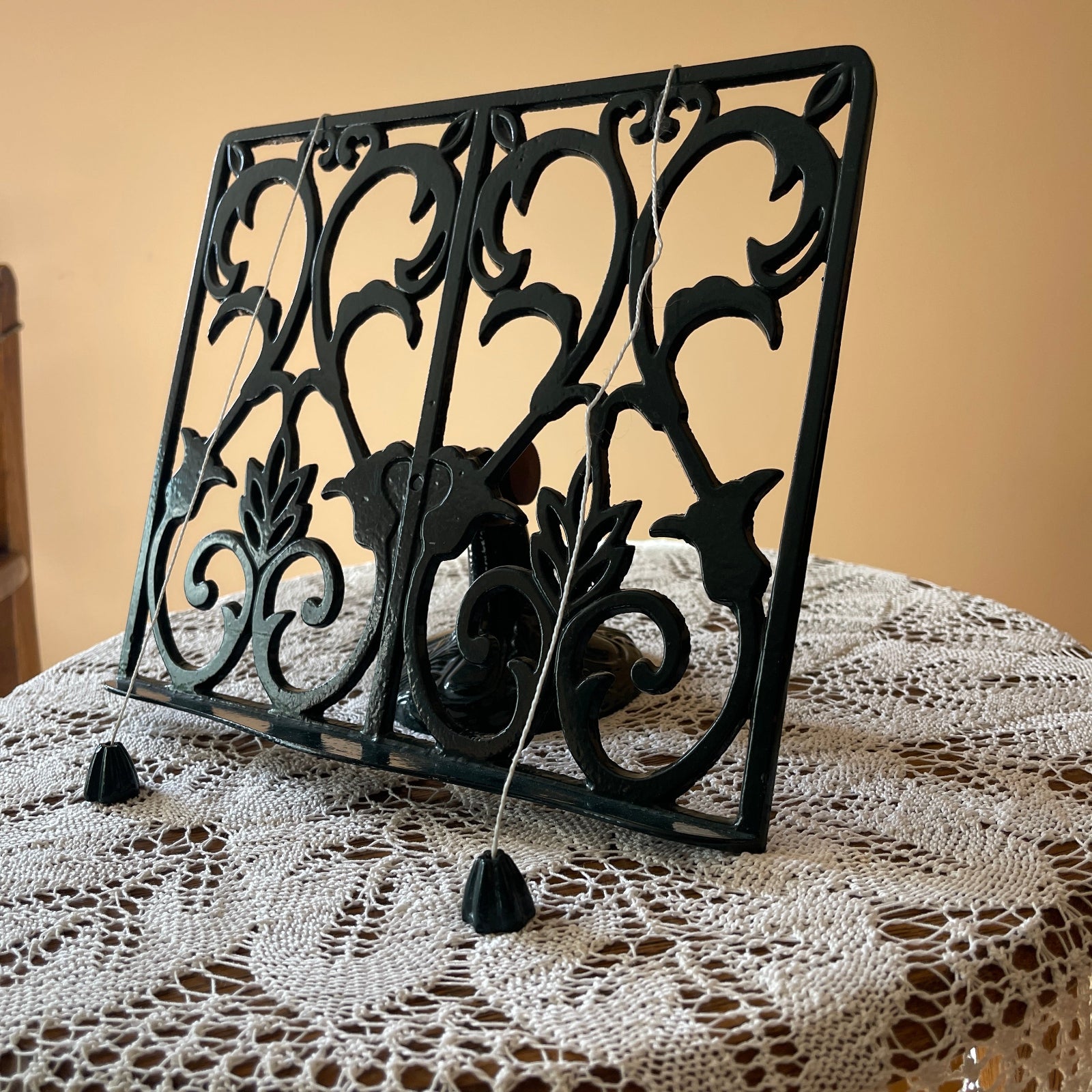 Decorative black metal book stand on a lace tablecloth with a beige background