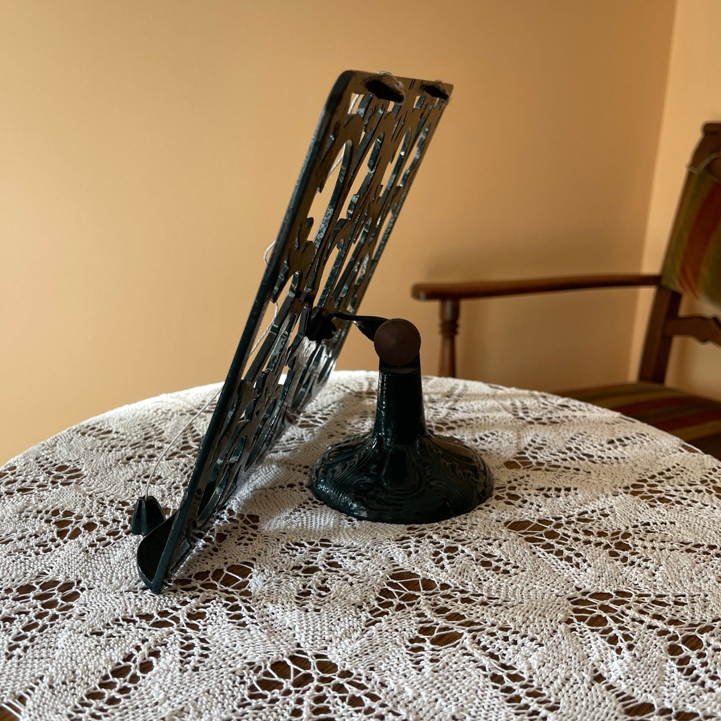 Decorative metal stand on a lace tablecloth with a wooden chair in the background