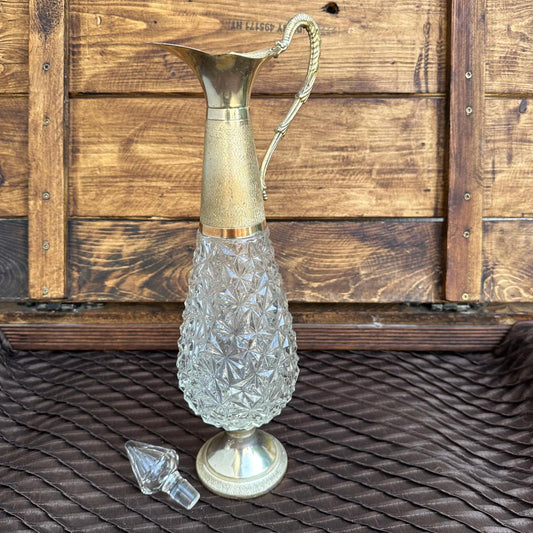 Decorative glass pitcher with a gold handle on a wooden surface