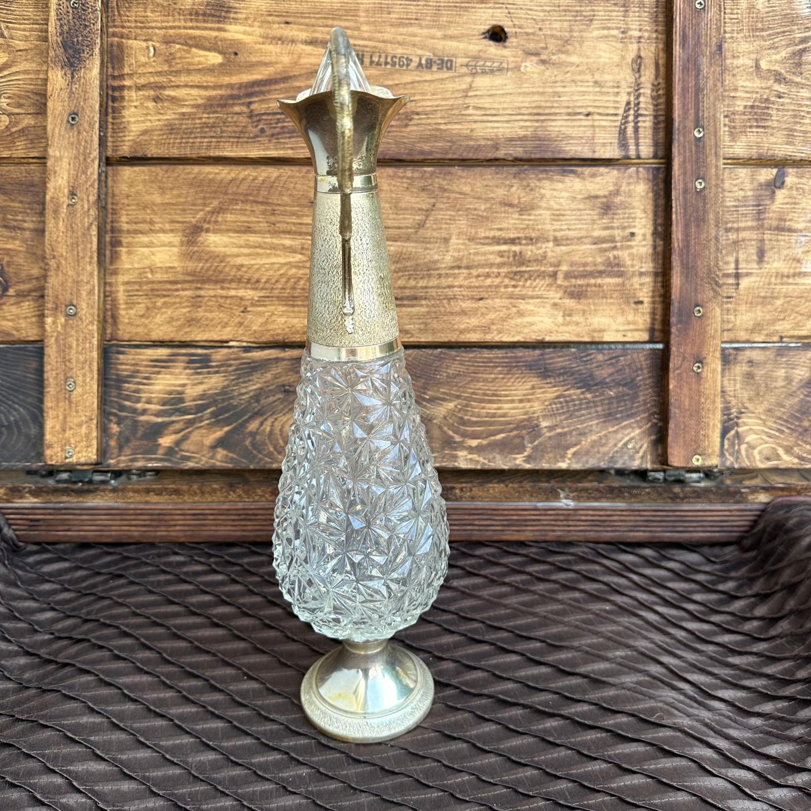 Decorative glass vase with metallic top on a textured surface with wooden background